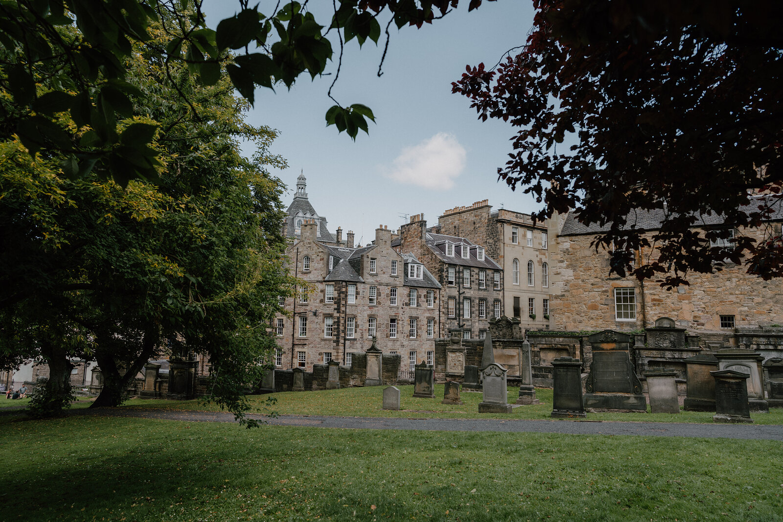 Weathered gravestones stand before tenement buildings at Greyfriars Kirkyard.