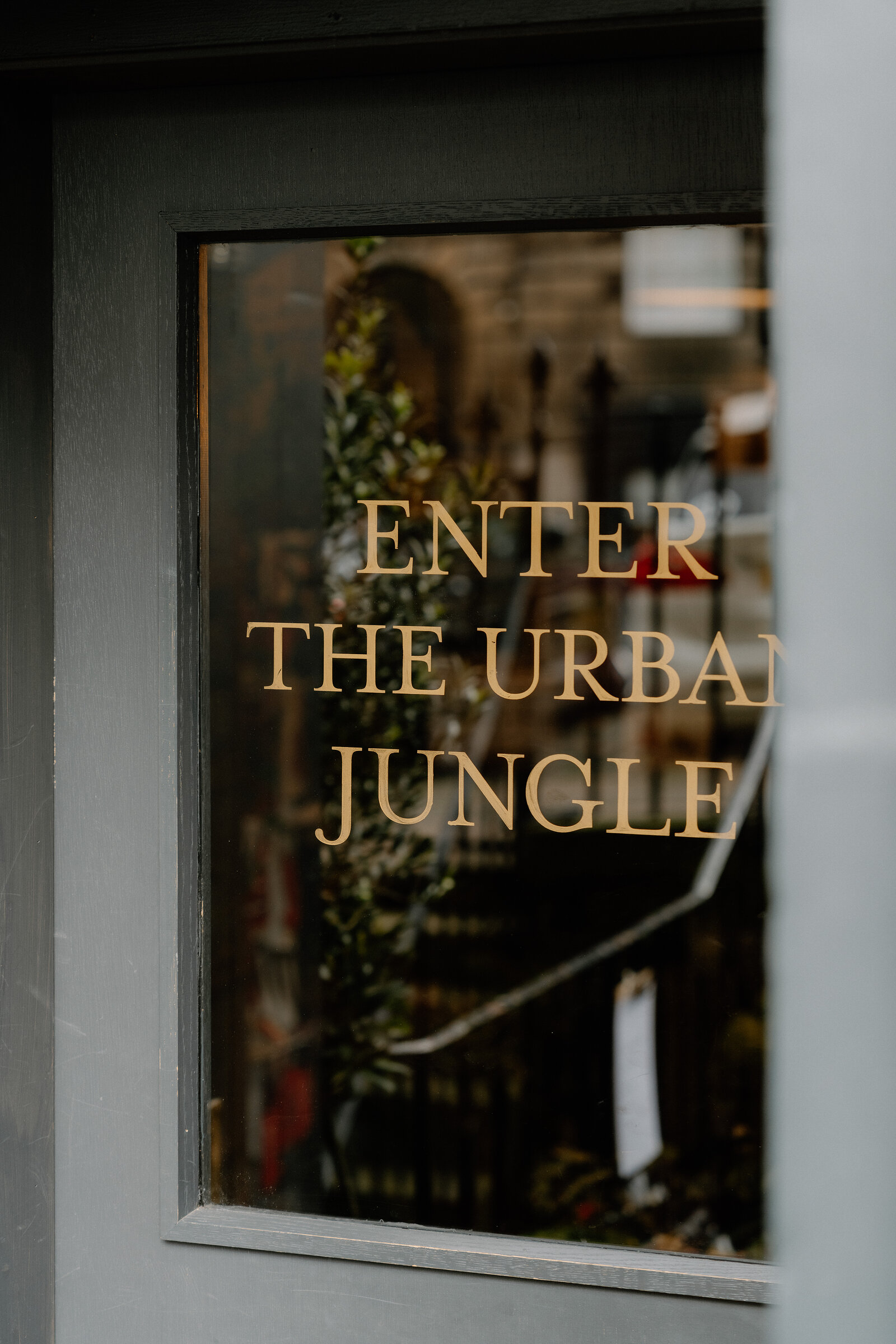 Gold lettering reading 'Enter the Urban Jungle' is etched on a door window at grow urban.