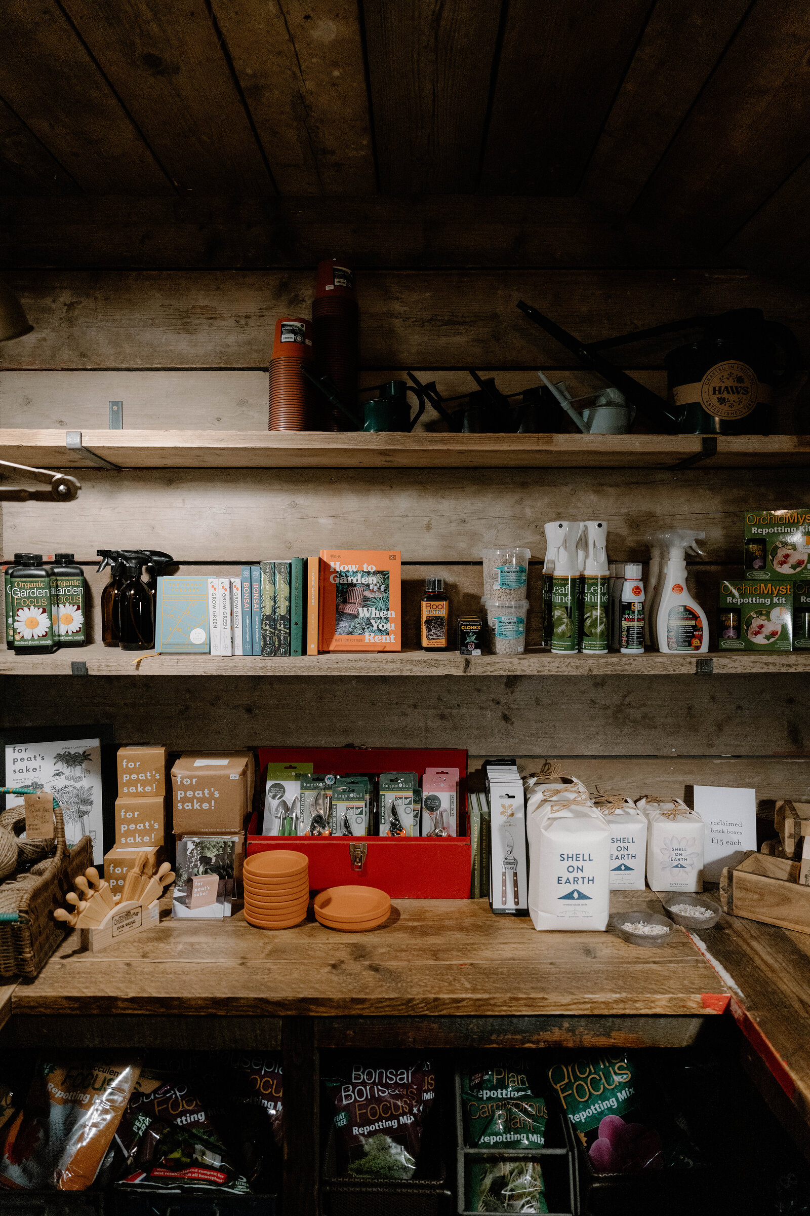 Garden sprays, tools and potting supplies fill wooden shelves at grow urban.