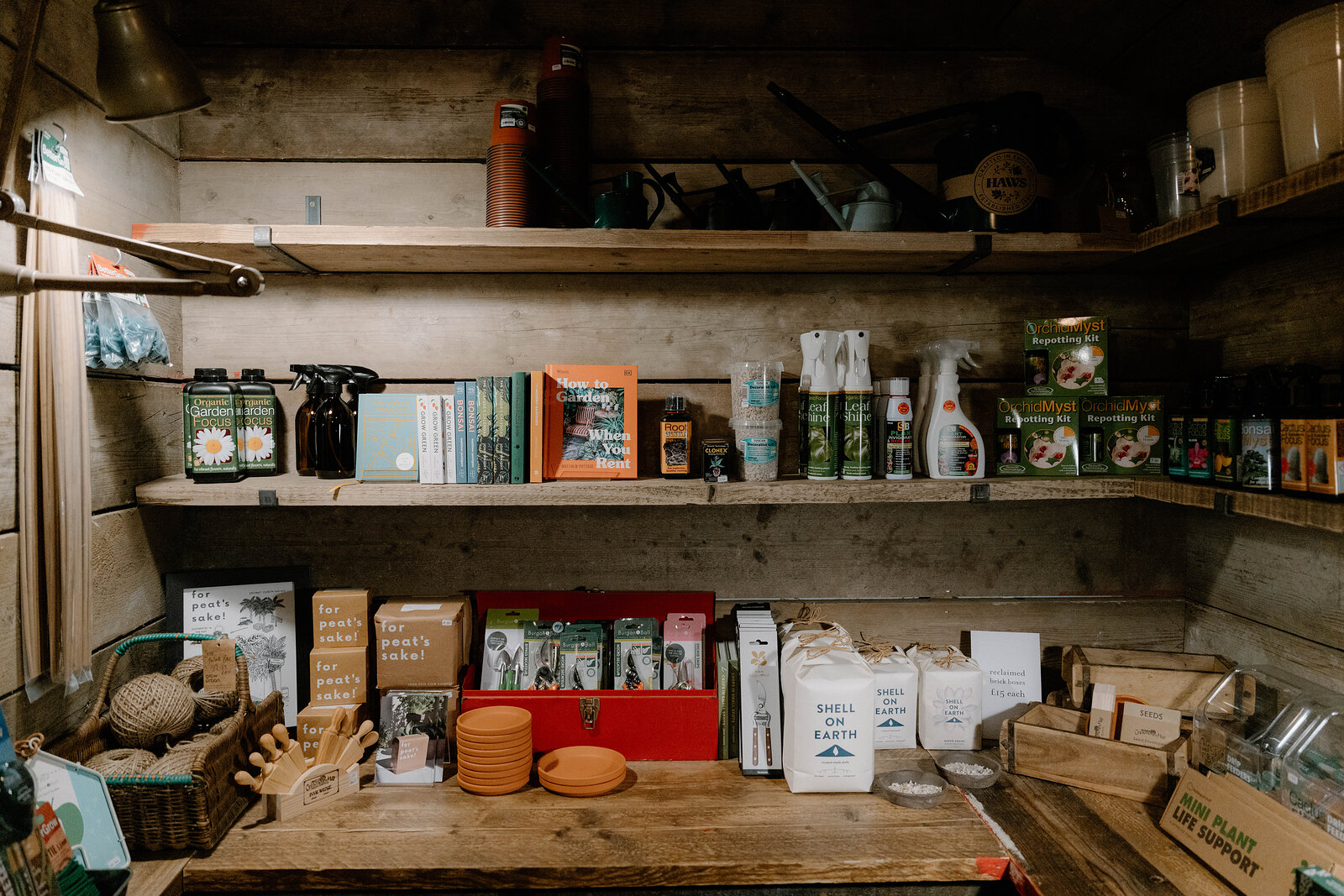 Potting soil, spray bottles and garden books fill a wooden shed shelf at grow urban.