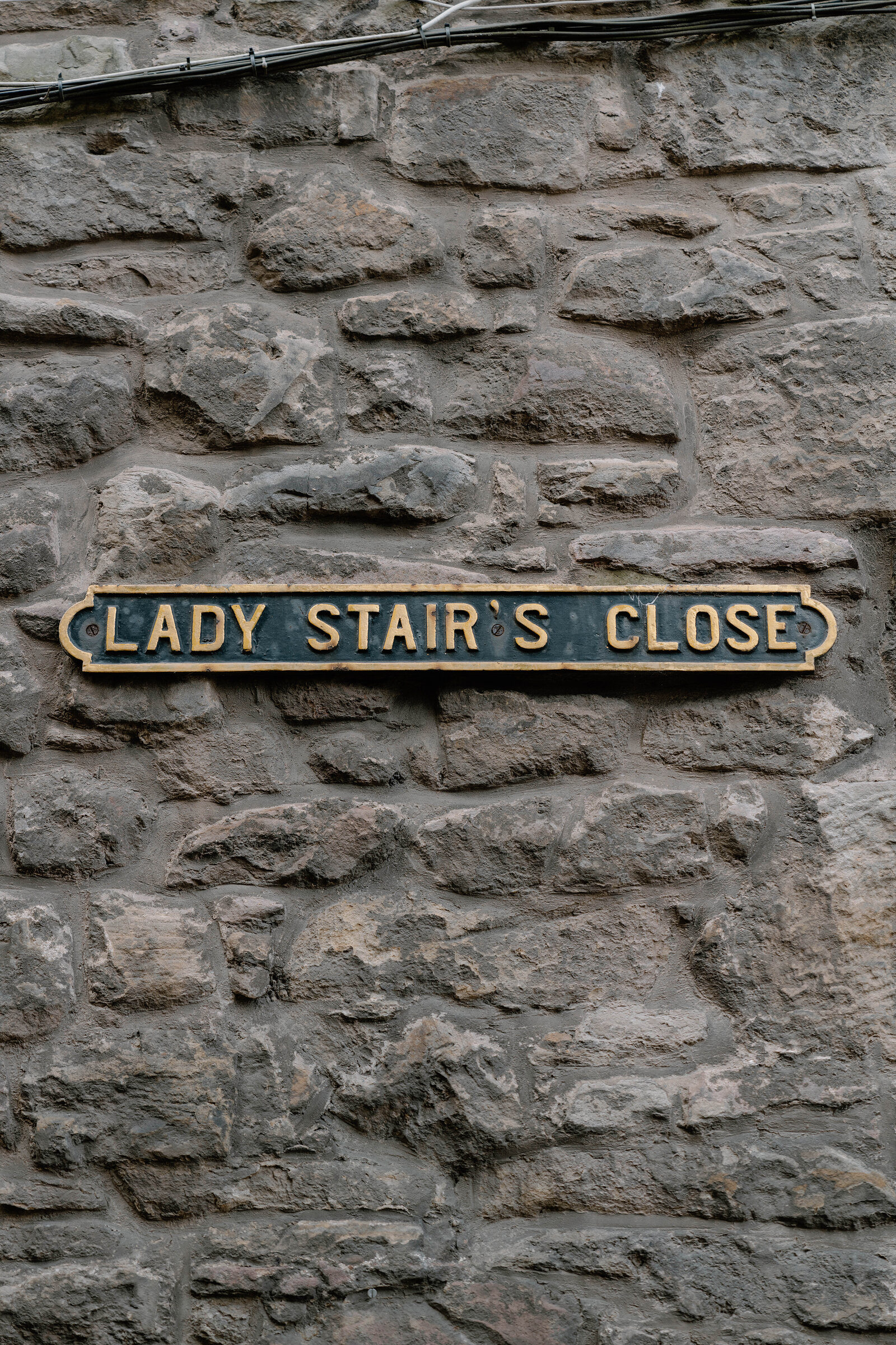 A weathered stone wall carries a street sign reading 'LADY STAIR'S CLOSE'.