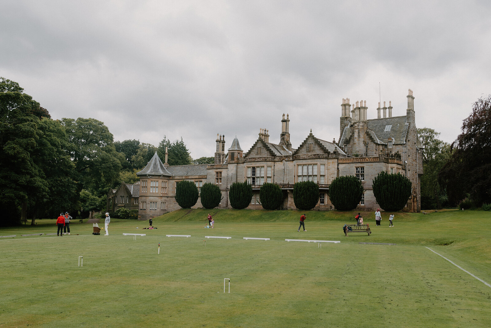 Players take part in a croquet match on the lawn before Lauriston Castle's turreted facade.