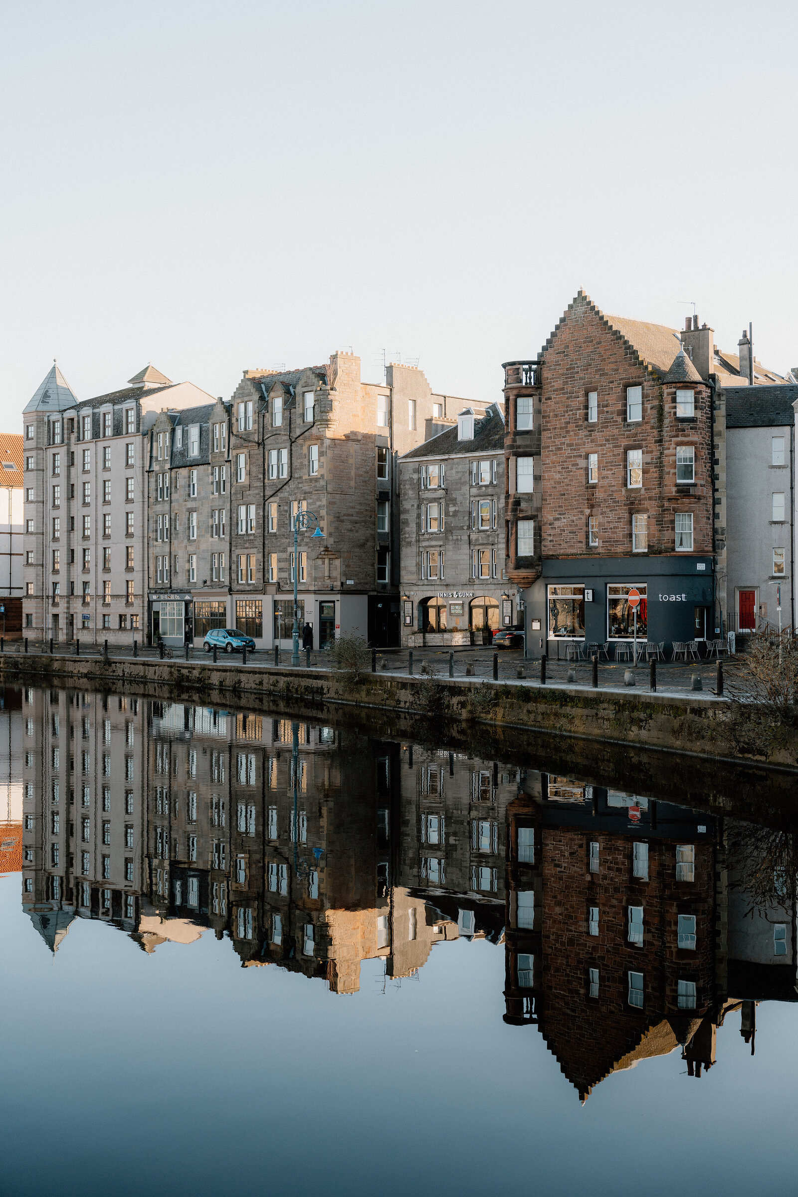 Tenement buildings along the Shore in Leith are mirrored in the still water below.