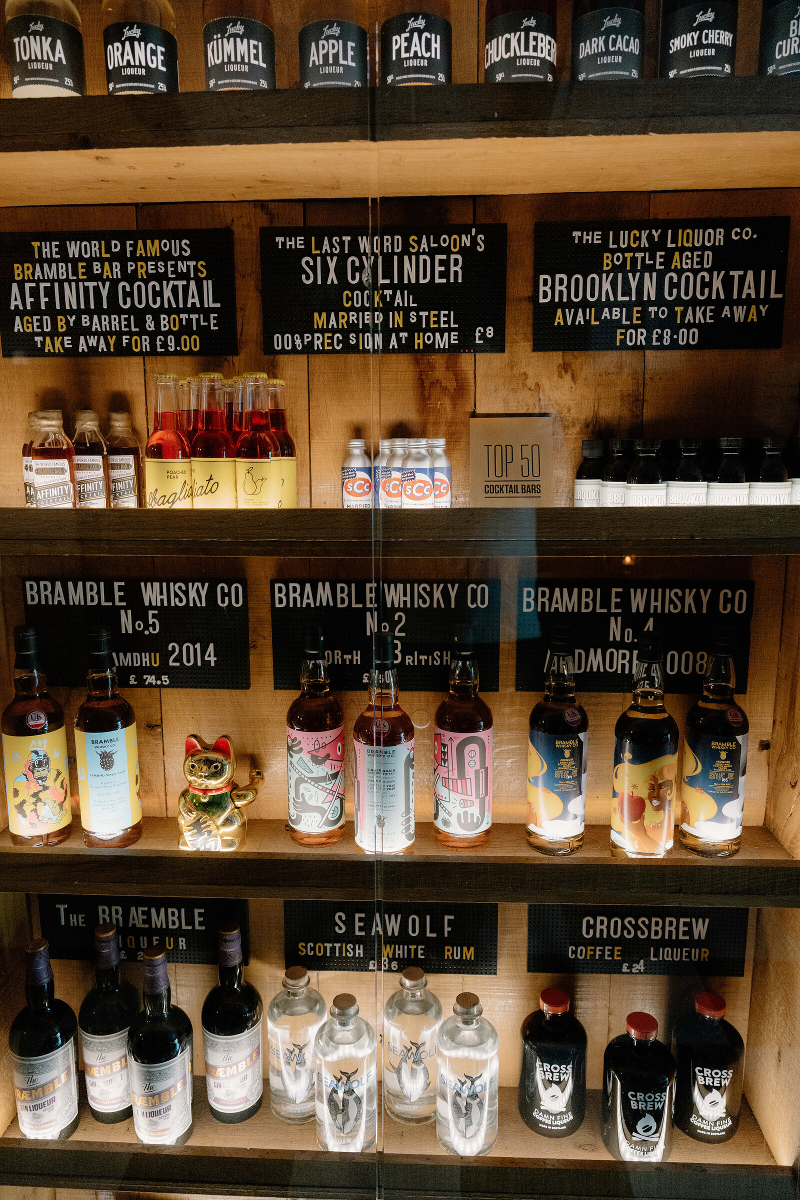 Bottles of Bramble Whisky Co and cocktail menu boards line shelves in an Edinburgh drinks shop.