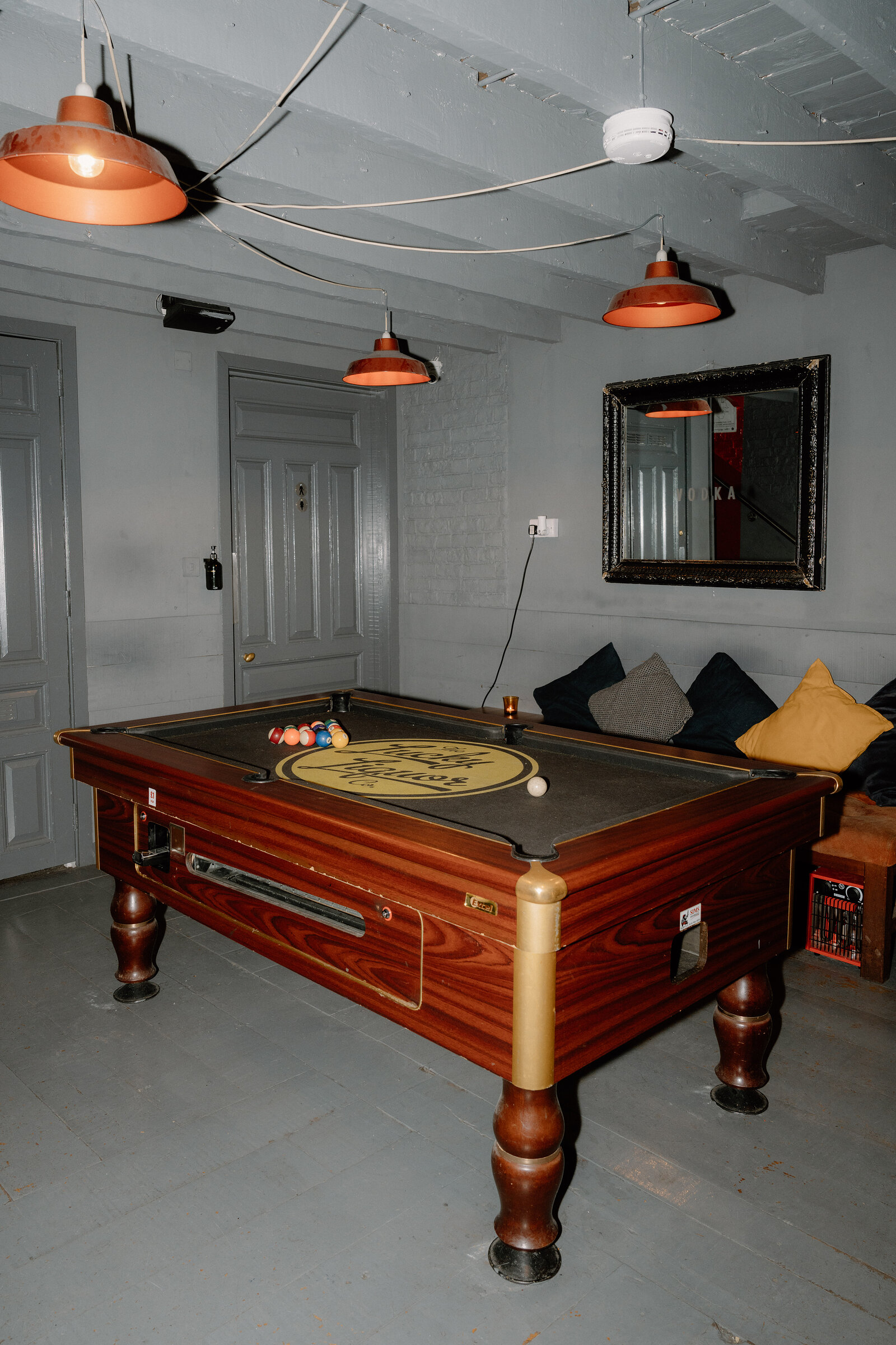 A pool table branded The Lucky Liquor Co sits beneath copper pendant lights in a basement bar in Edinburgh.