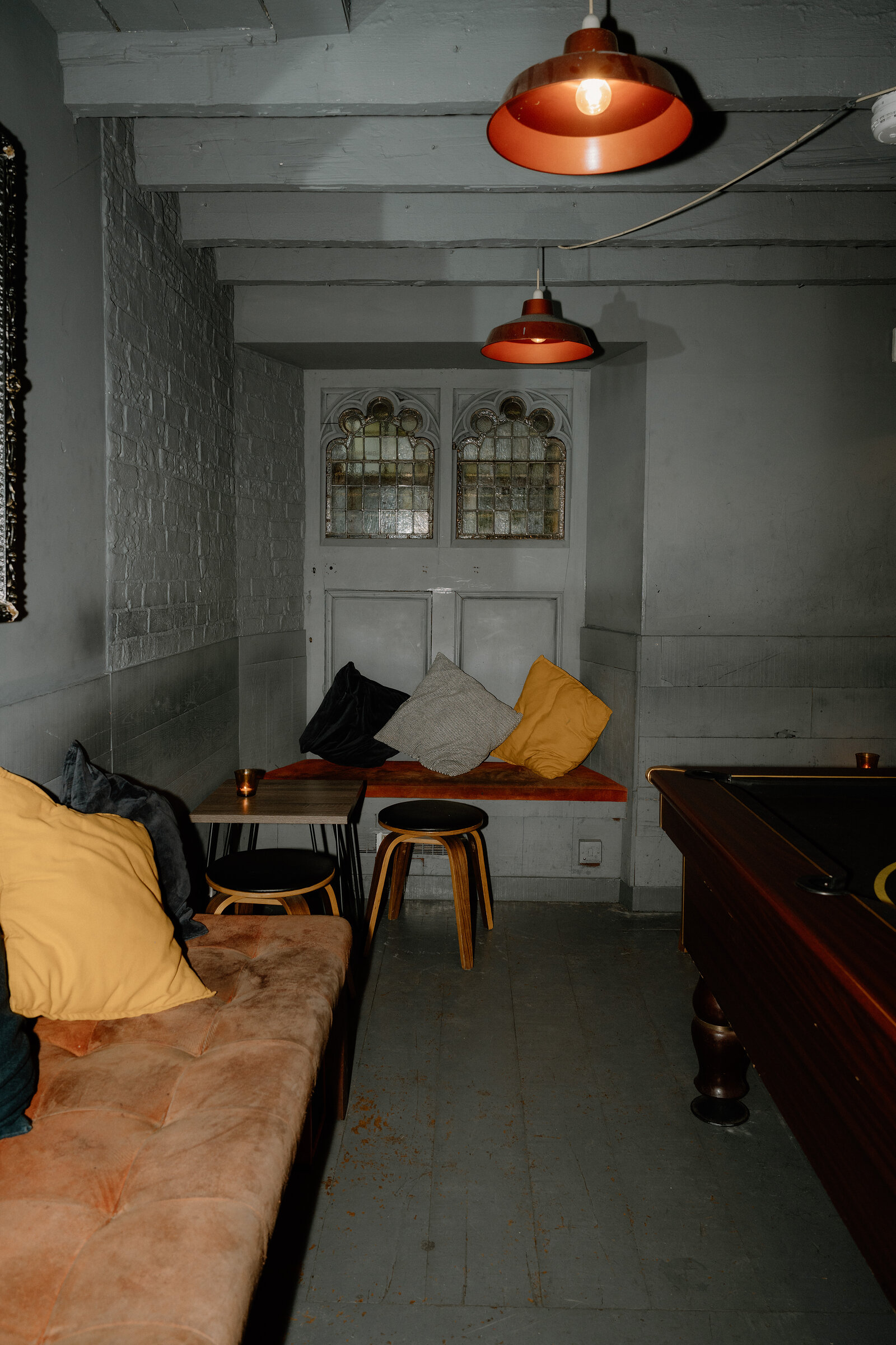 A stained-glass cupboard and cushioned bench sit in a dim alcove of an Edinburgh basement bar.