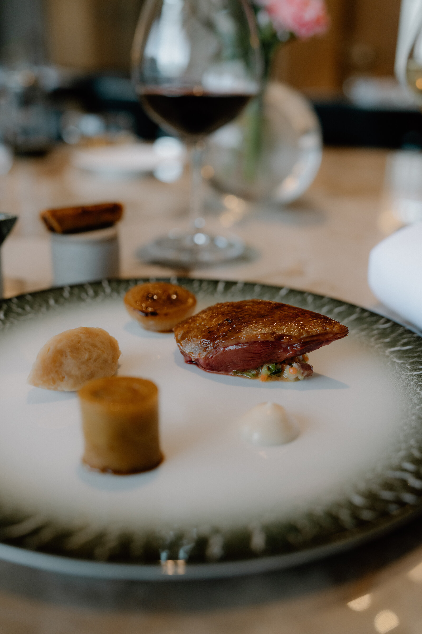 A seared duck breast is plated with a pastry roll and puree in an Edinburgh restaurant.