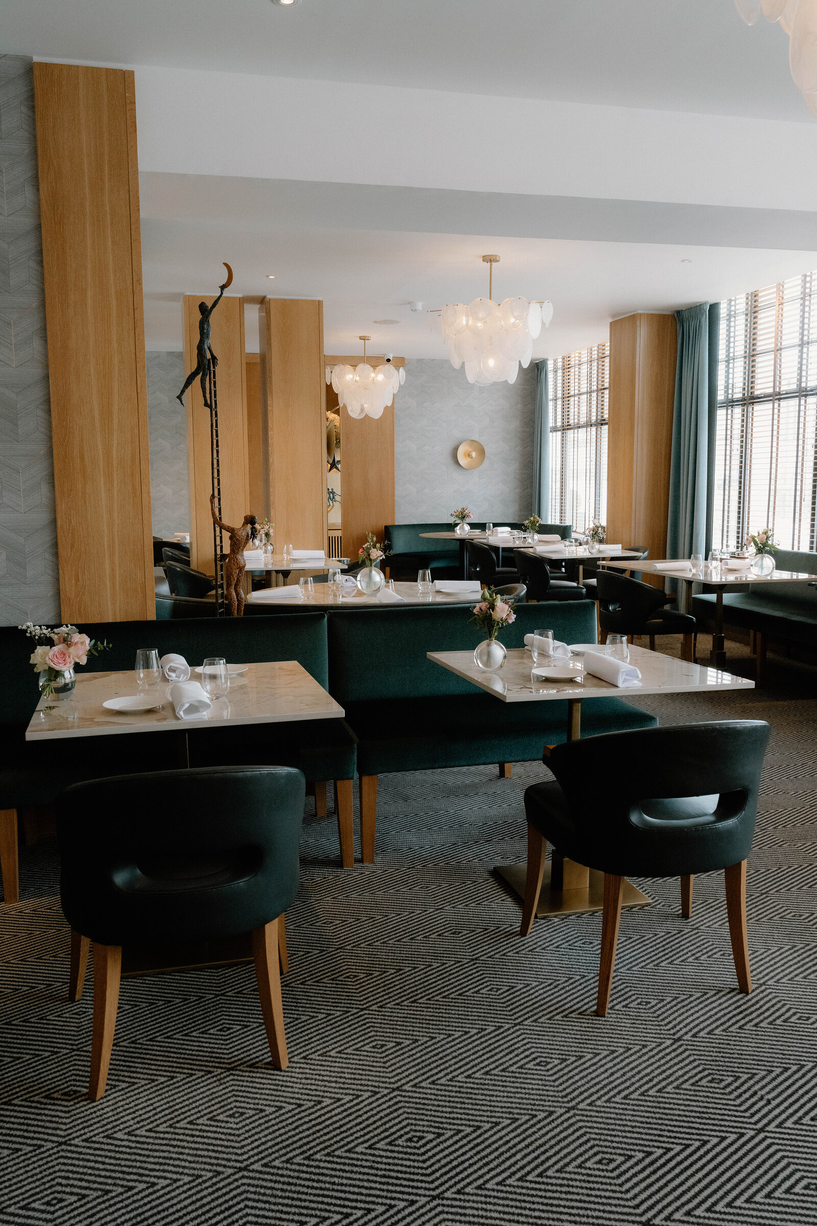 A bronze sculpture stands between timber-panelled booths in an Edinburgh restaurant dining room.
