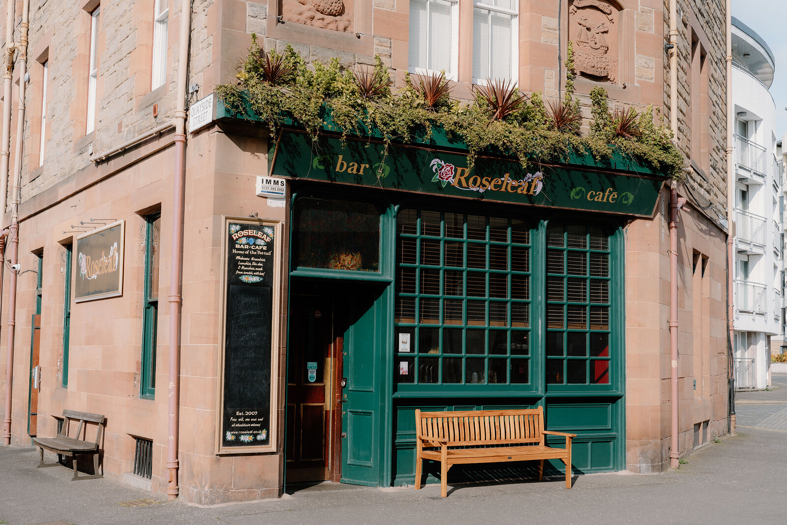 Rosecleft's green corner shopfront sits below carved sandstone panels, a chalkboard menu beside the door.