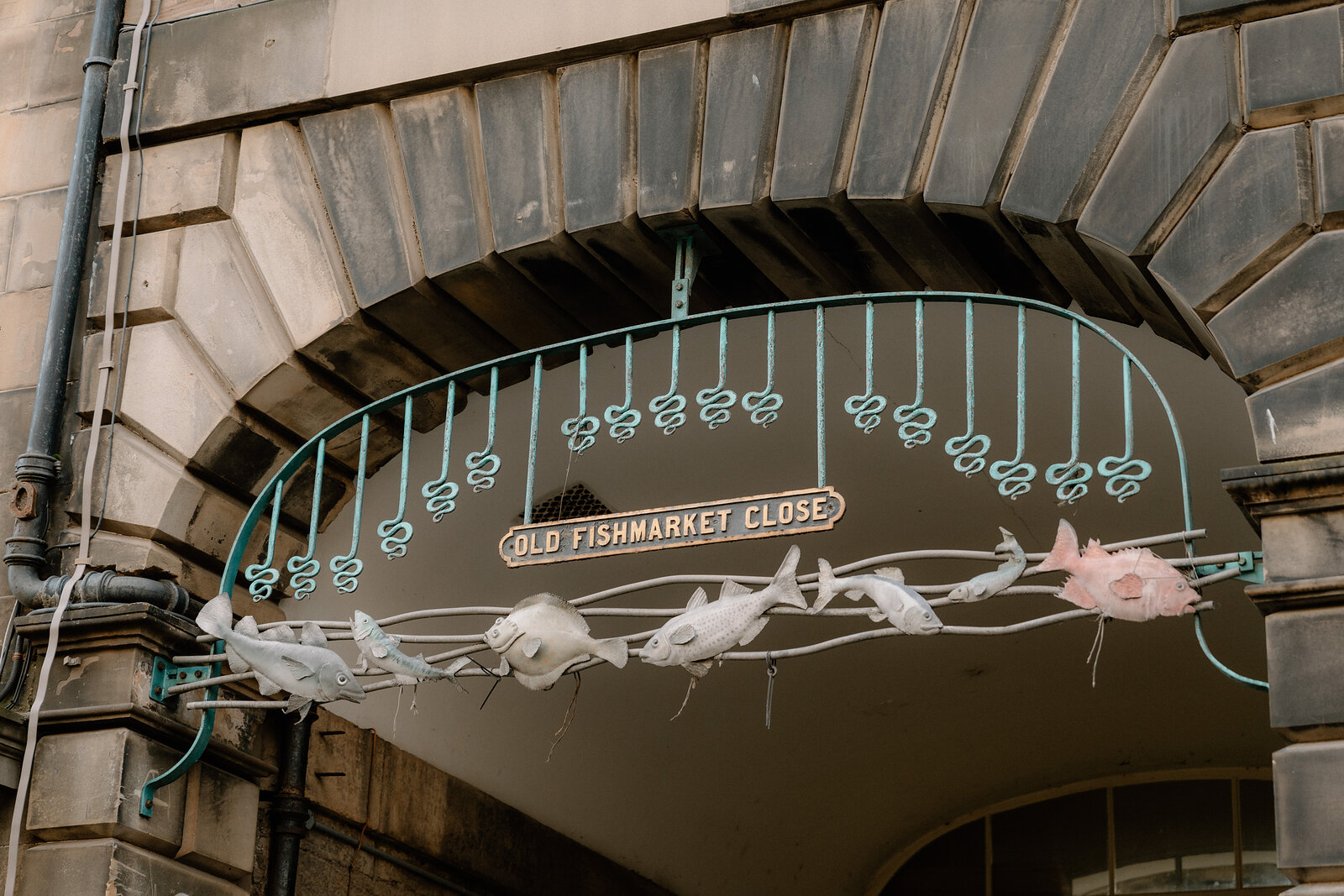 A decorative arch reading 'Old Fishmarket Close' is hung with fish-shaped ornaments.