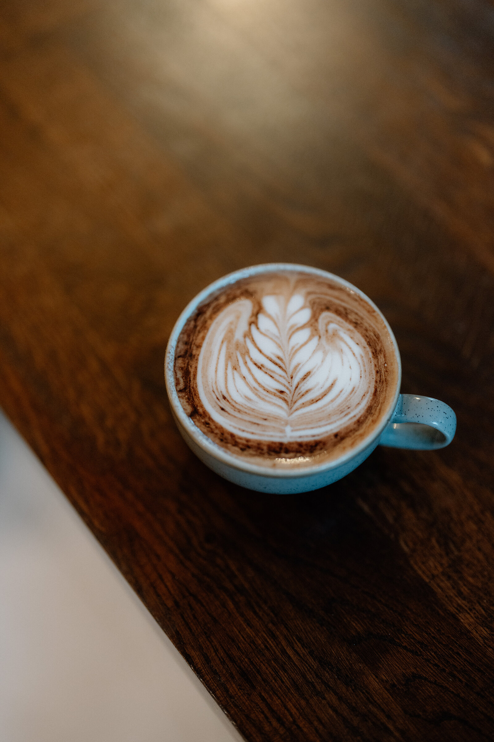 A cup of latte art sits on a dark wooden table.