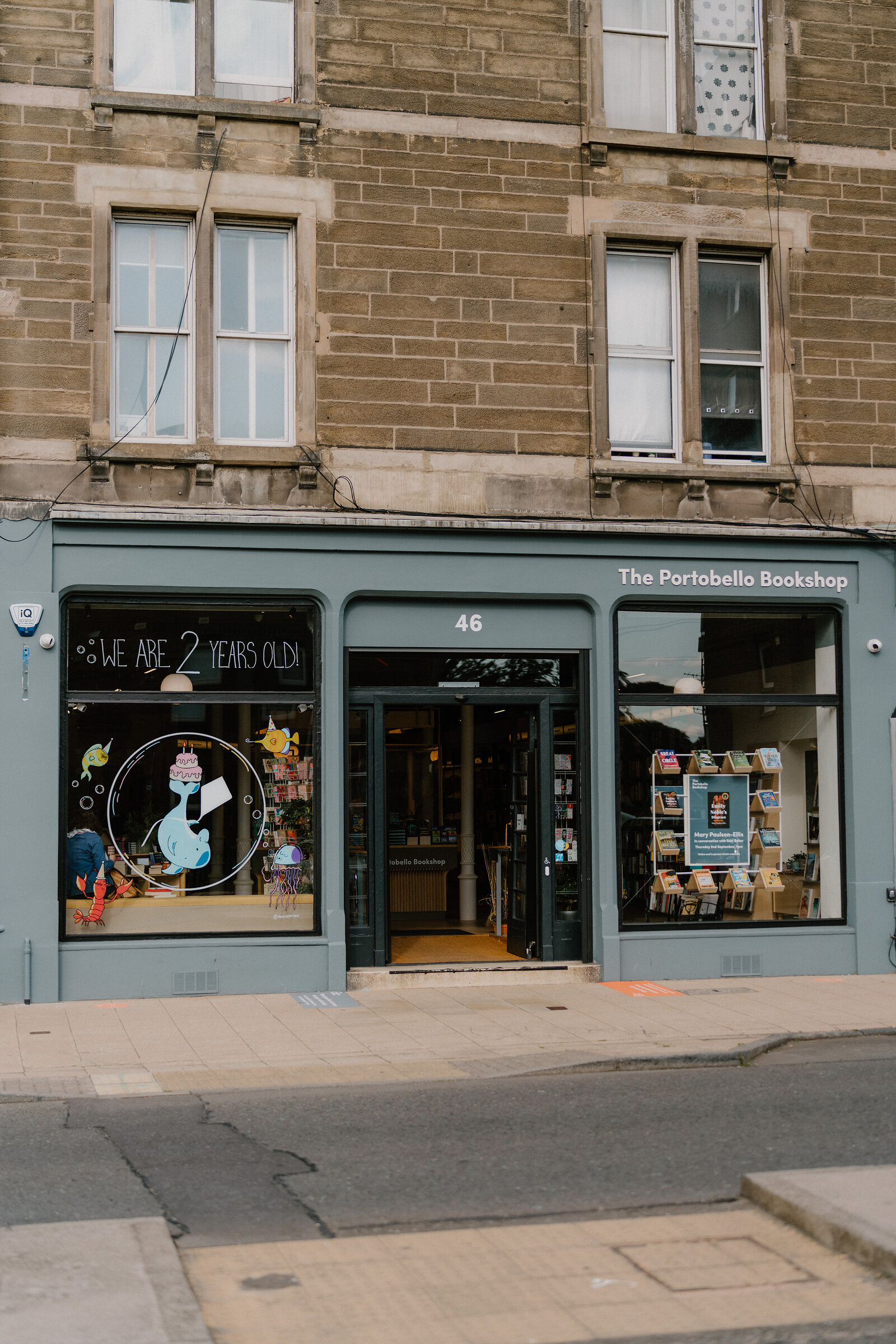 A sign reading 'The Portobello Bookshop' marks a green-painted corner shopfront with a '2 years old' window display.