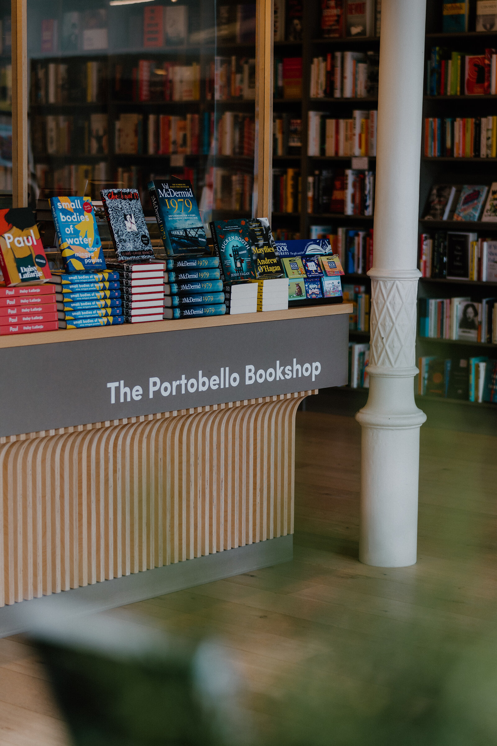 A display table of books stands before a sign reading 'The Portobello Bookshop' beneath tall bookshelves.