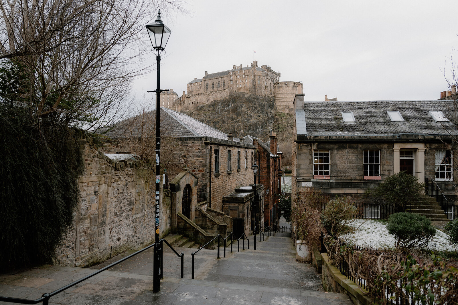 A stepped street lined with sandstone buildings leads toward Edinburgh Castle on its rock.