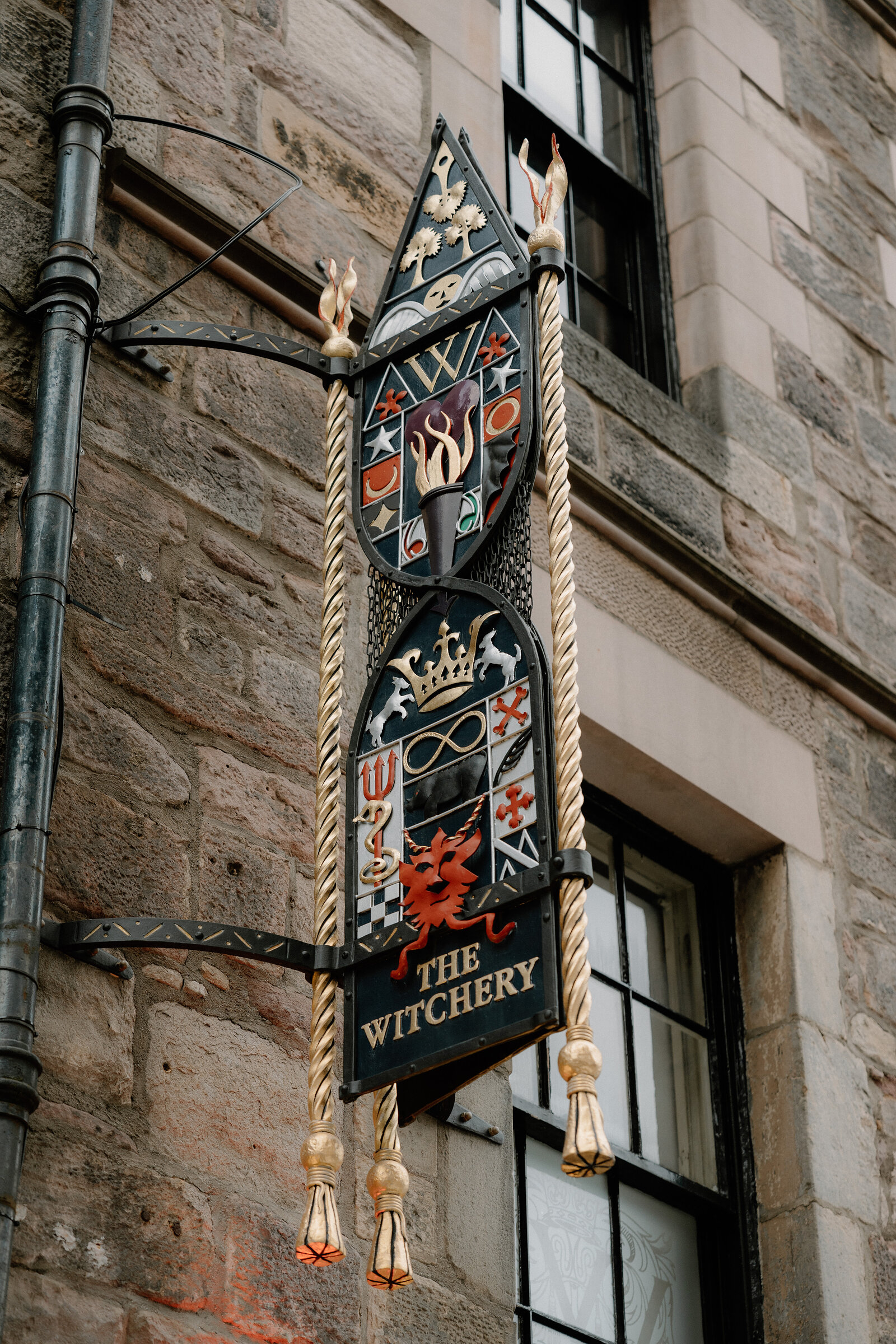 An ornate hanging sign reading 'The Witchery' bears a coat of arms and gold tassels.