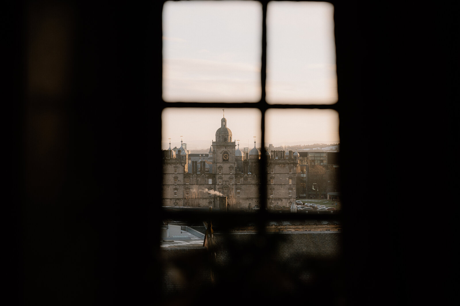 A domed building with a clock tower rises above the city, seen through a small window.