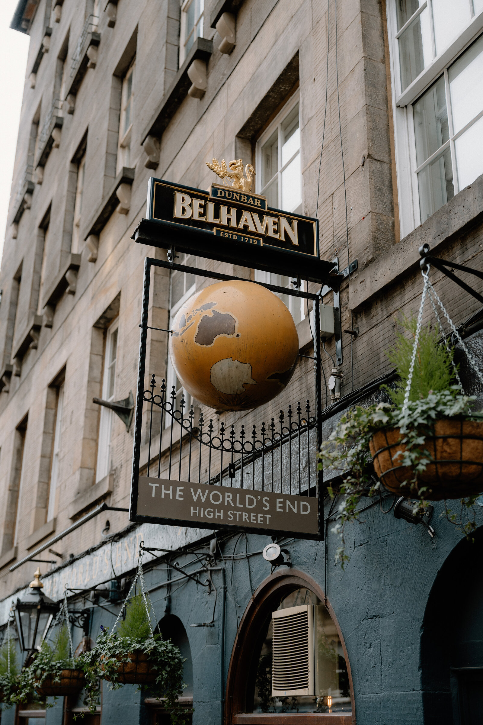 A hanging sign for 'The World's End' shows a globe beneath a 'Belhaven' banner on High Street.