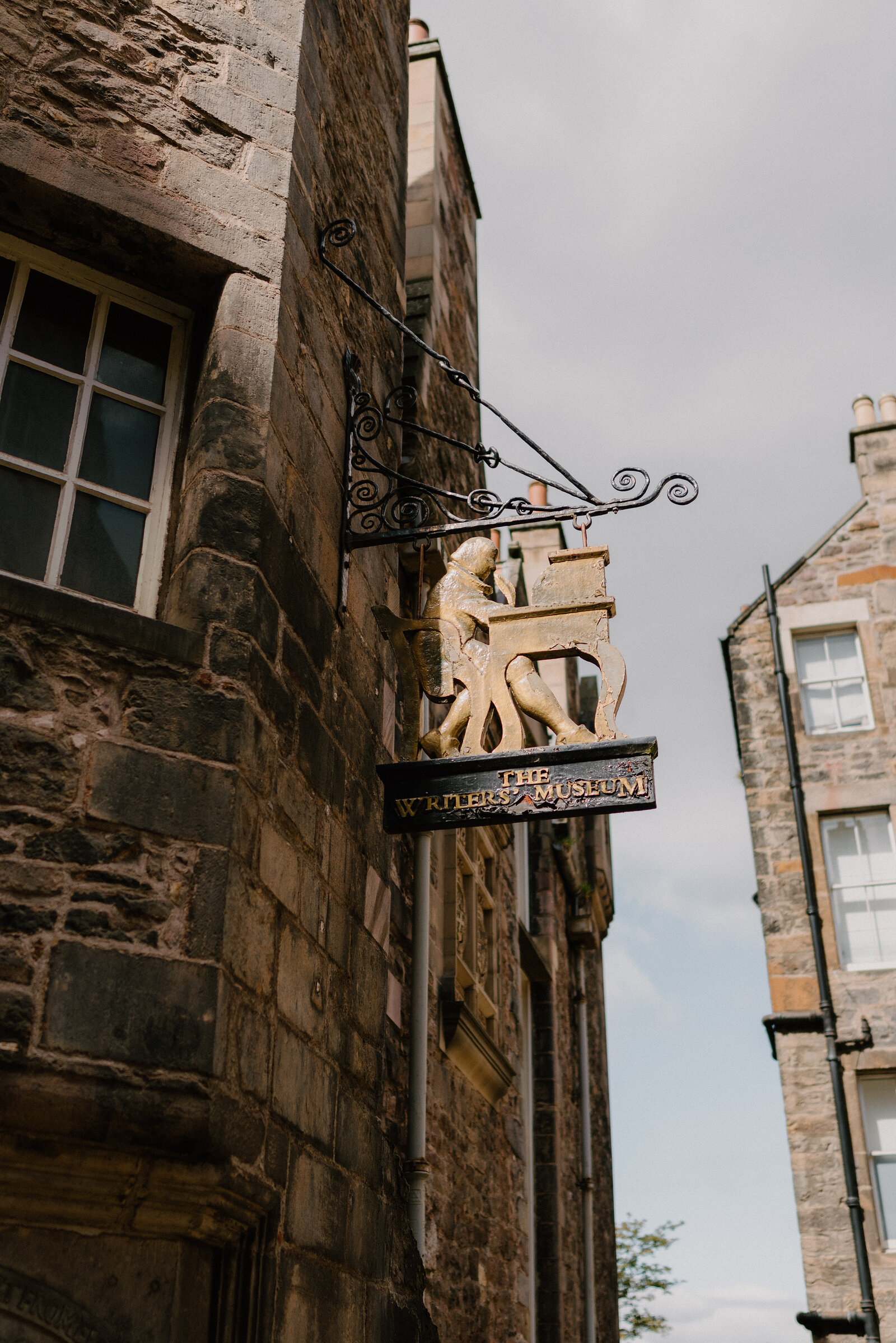 A carved hanging sign reads 'The Writers' Museum' beside a figure at a writing desk.