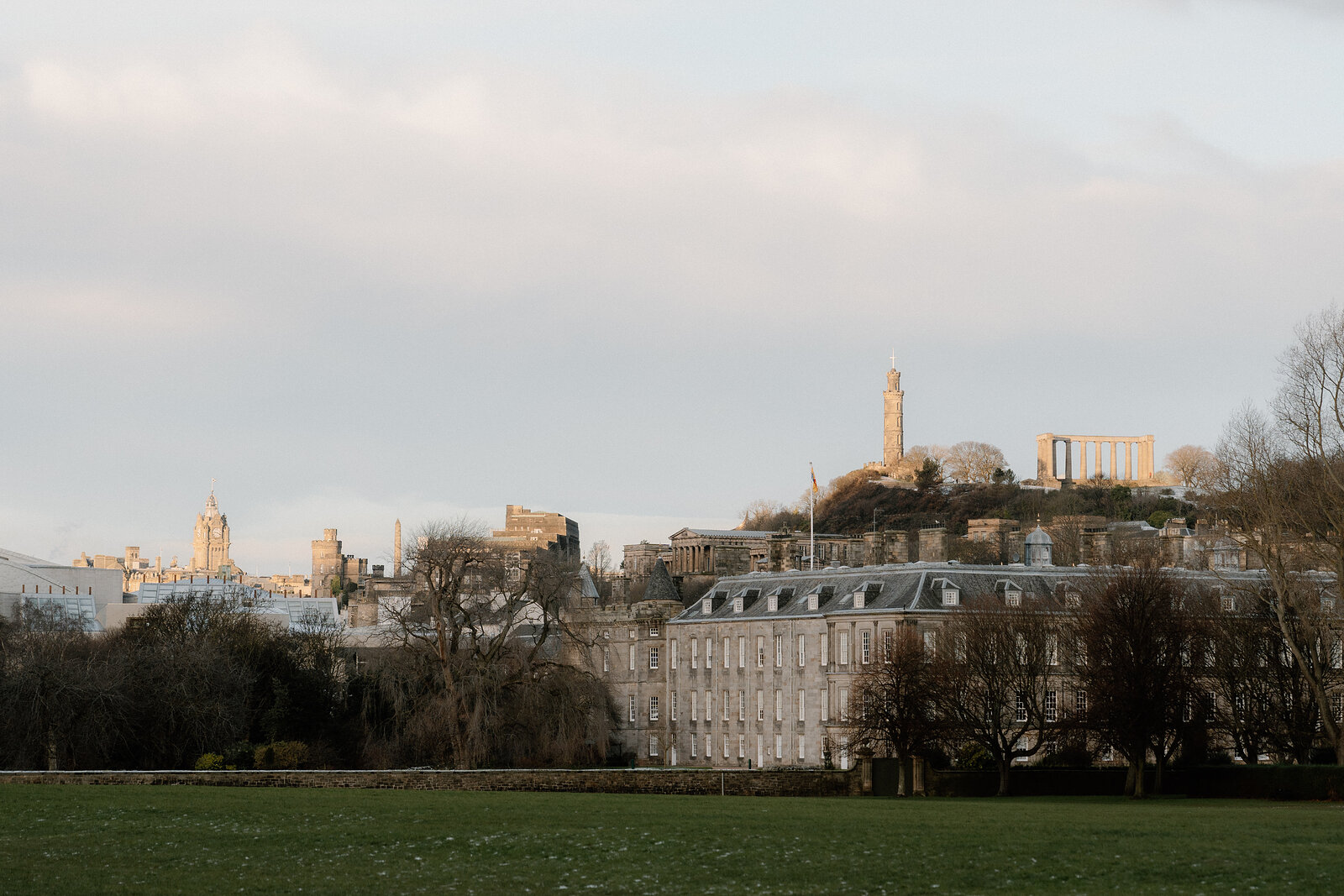 Calton Hill's monuments rise above a Georgian terrace and parkland, seen from Holyrood Park