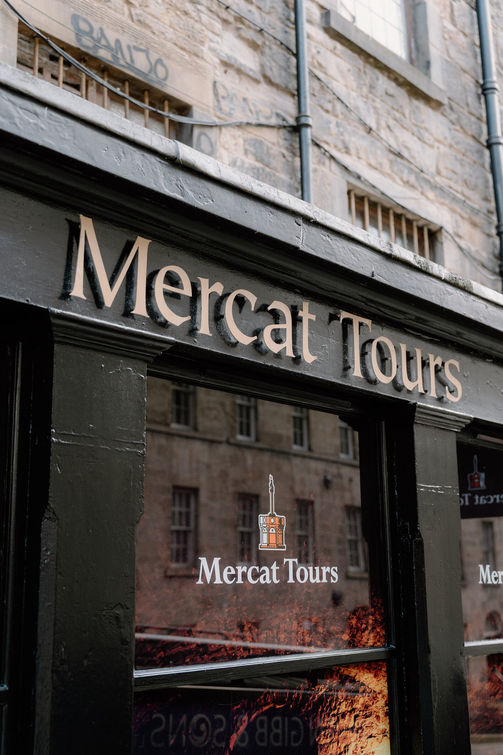 The "Mercat Tours" shopfront sign above a window displaying the company's crest