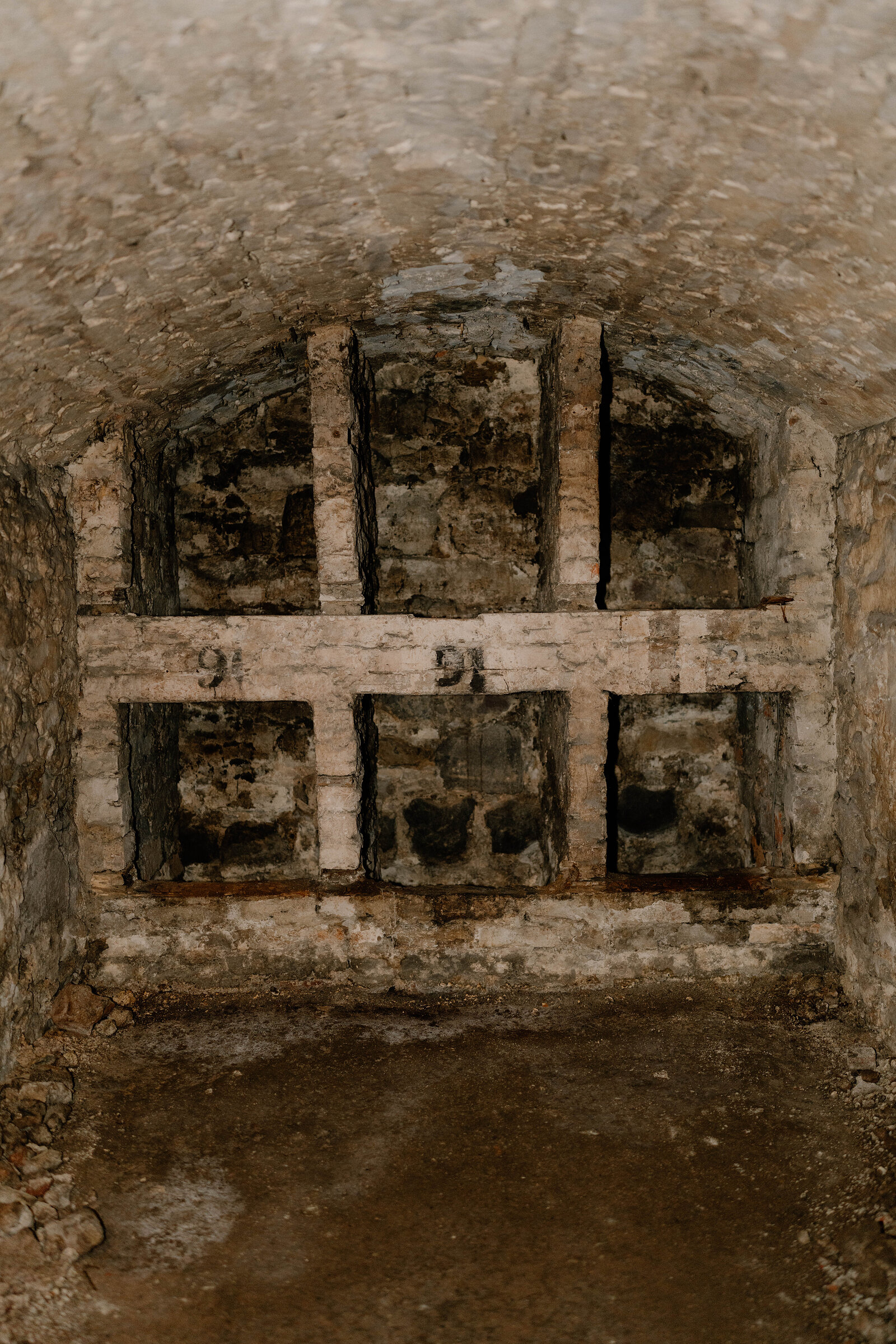 A vaulted stone chamber underground, numbered panels set into the brickwork