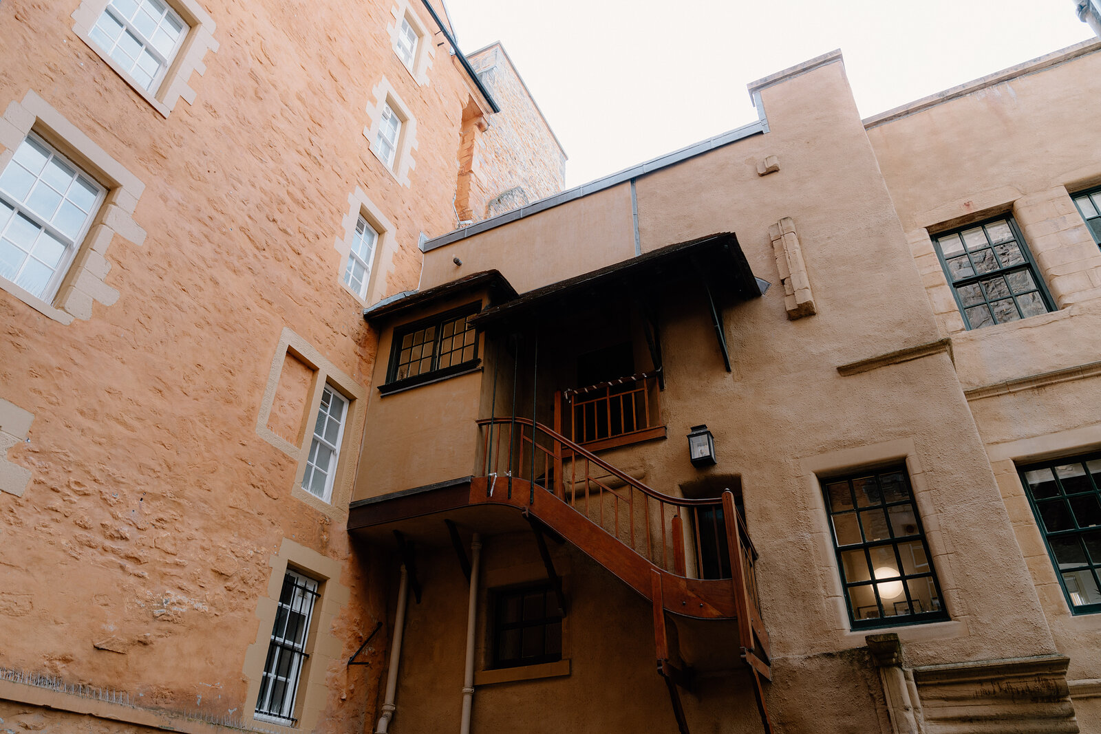A wooden stair and gallery climb the sandstone courtyard walls of Riddle's Court