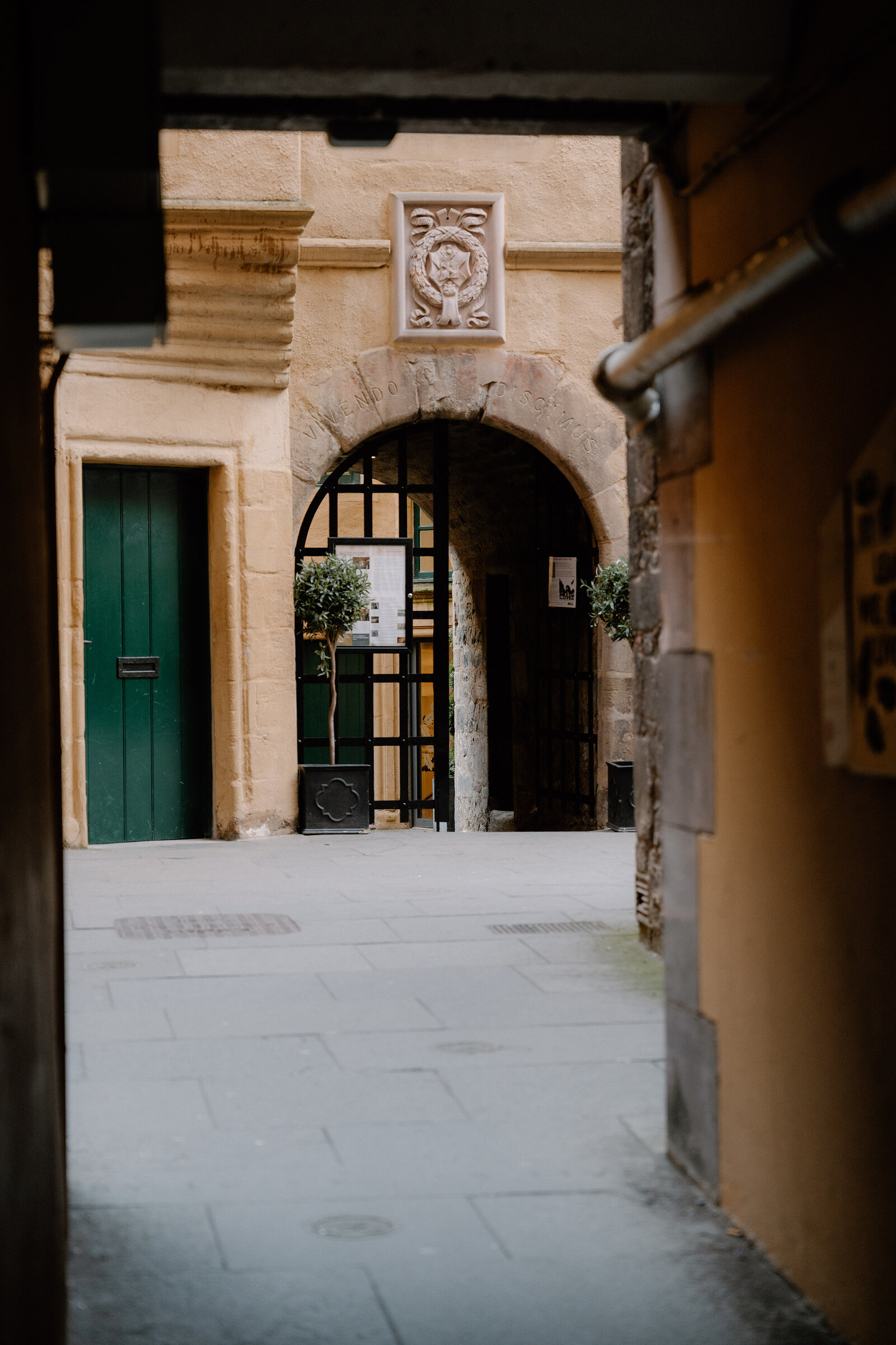 A stone archway carved with a crest, opening onto a quiet courtyard