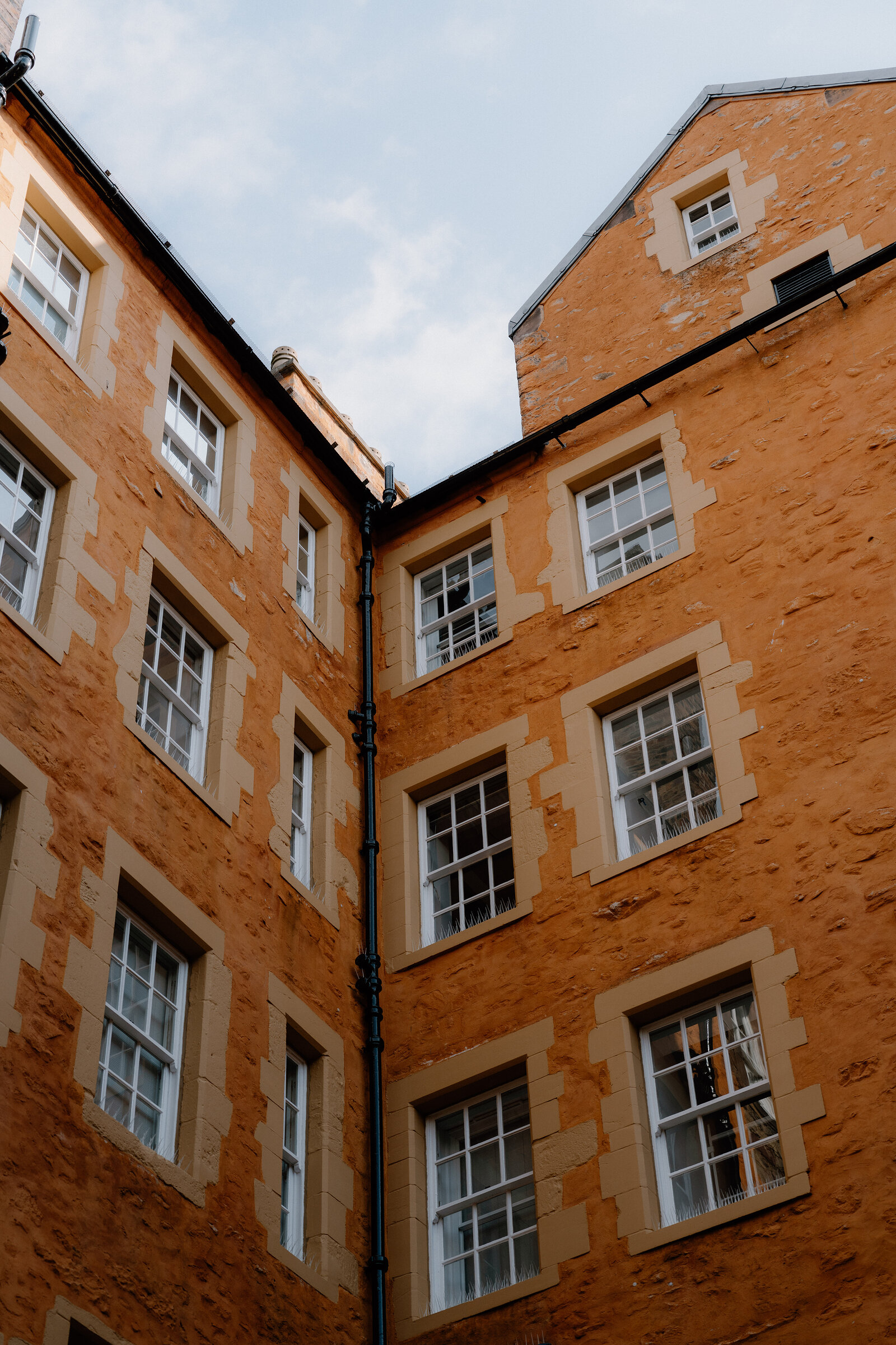 The ochre sandstone corner of a tenement courtyard, its windows trimmed in pale stone