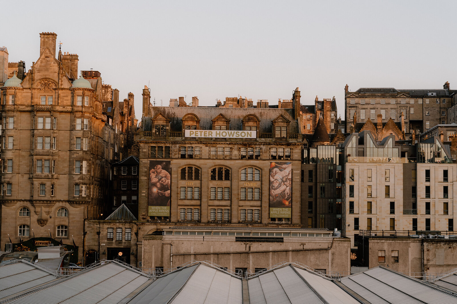A grand Edinburgh building hung with "Peter Howson" exhibition banners at dusk.