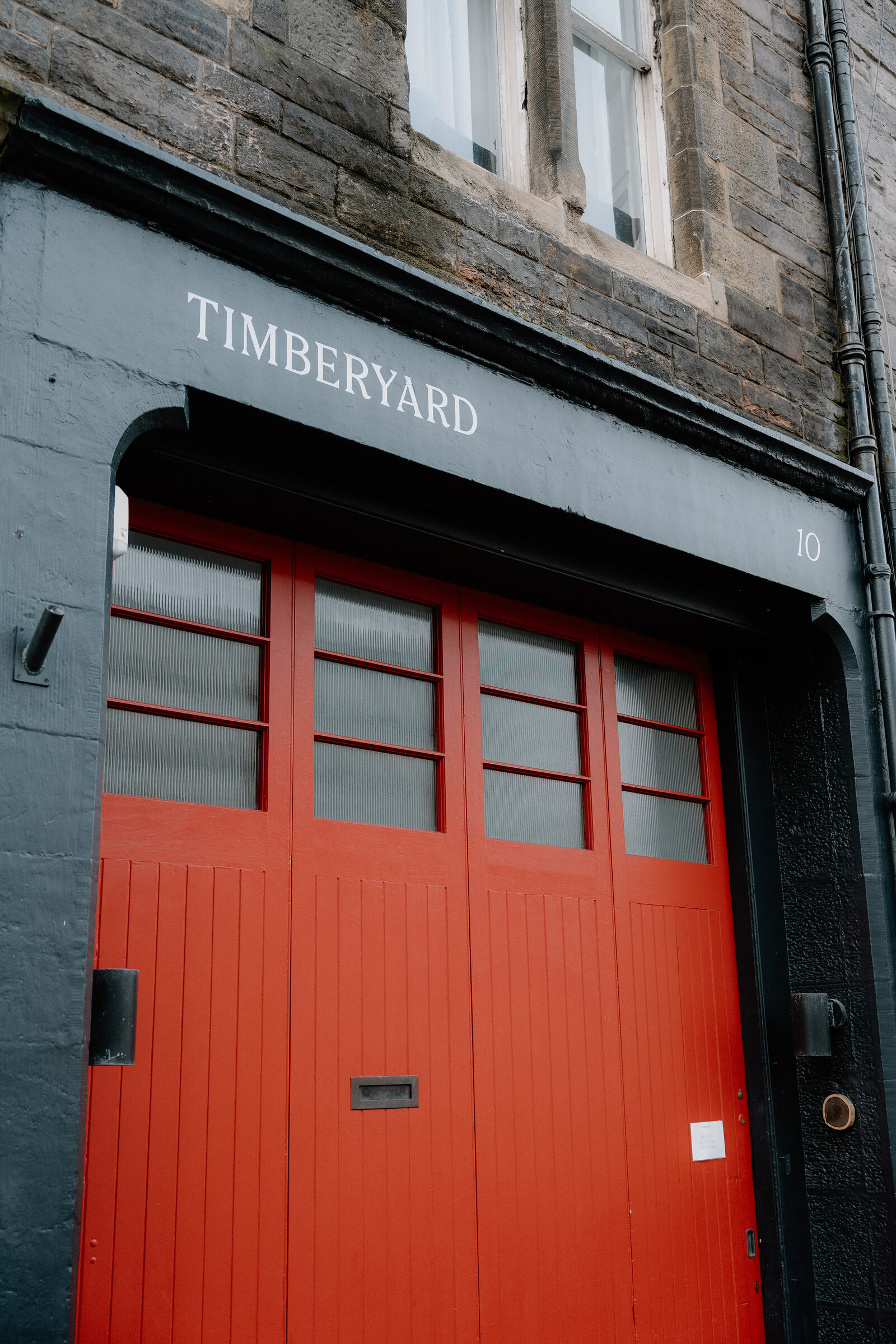 The Timberyard sign above red garage-style doors set into a stone and brick facade