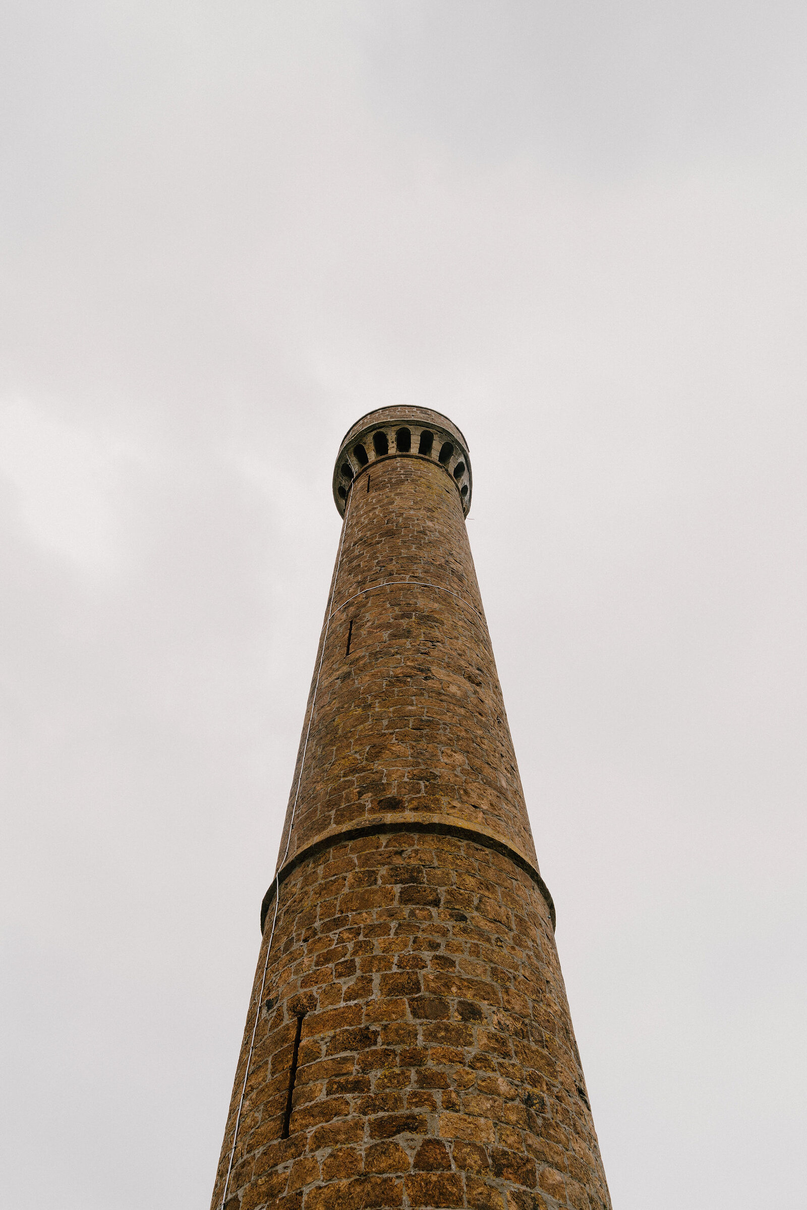 A tall stone tower rises against an overcast sky.