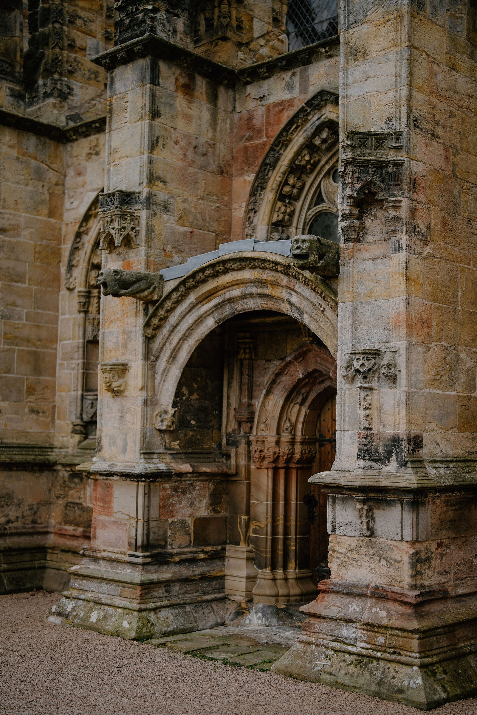 Carved gargoyles flank an arched doorway on Rosslyn Chapel's facade.