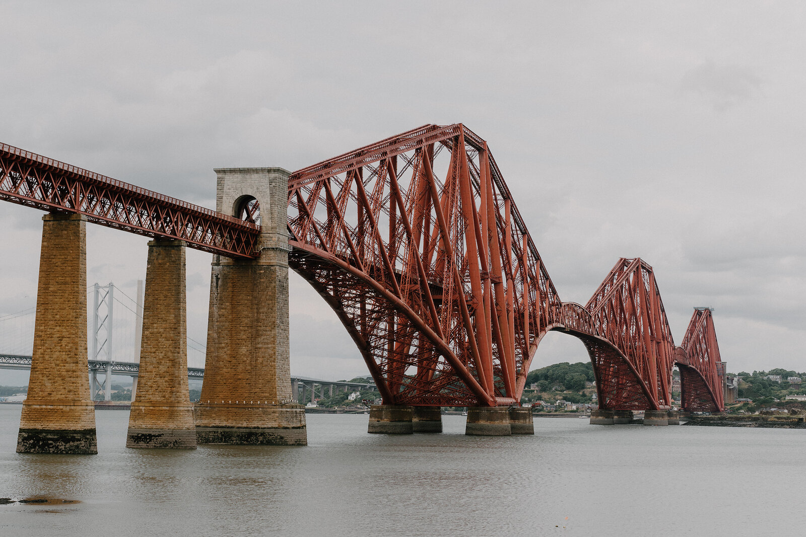 The Forth Bridge's red cantilevered spans rising from stone piers across the water