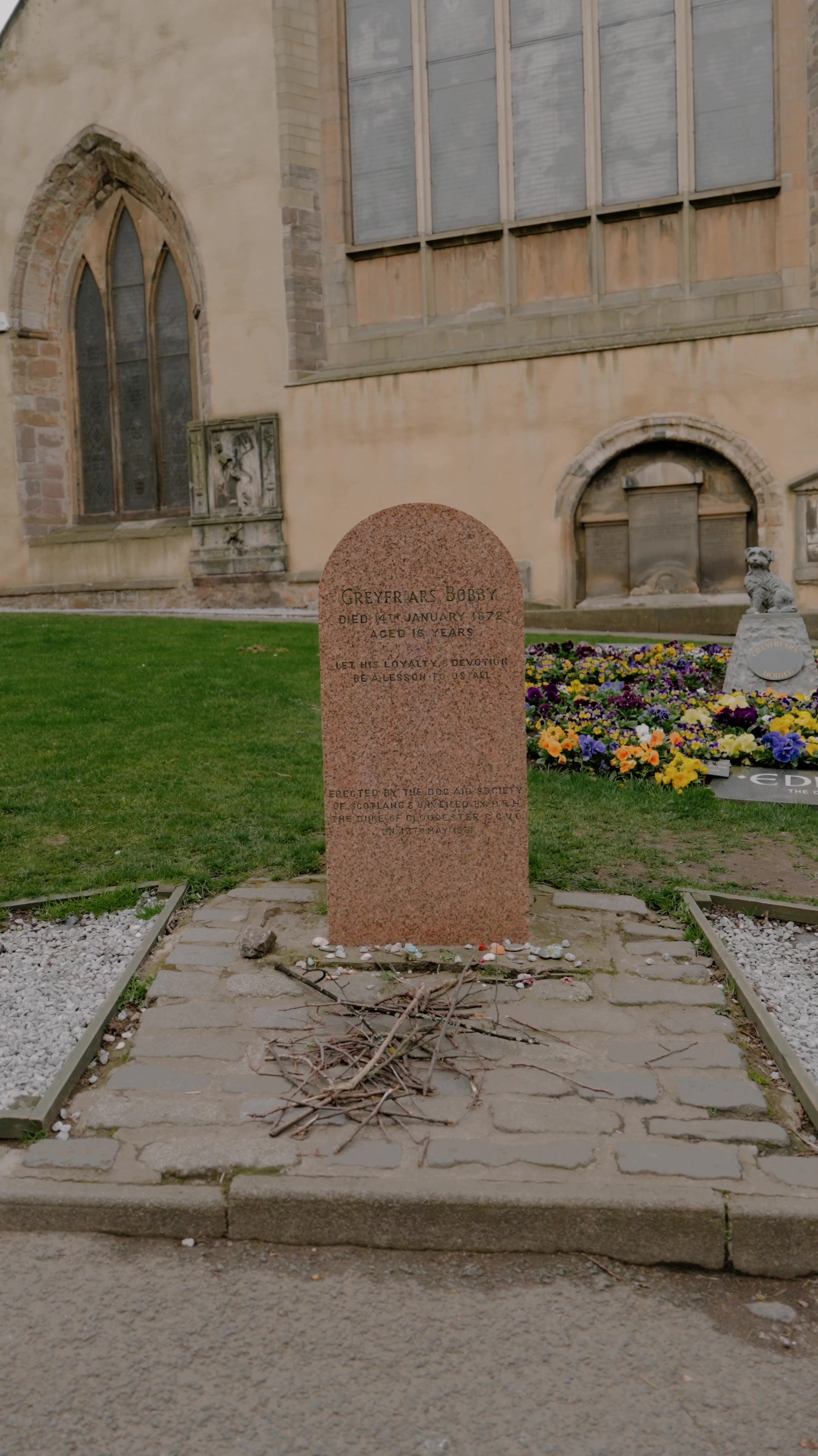 Greyfriars Bobby's headstone with the kirkyard church and a small statue visible behind