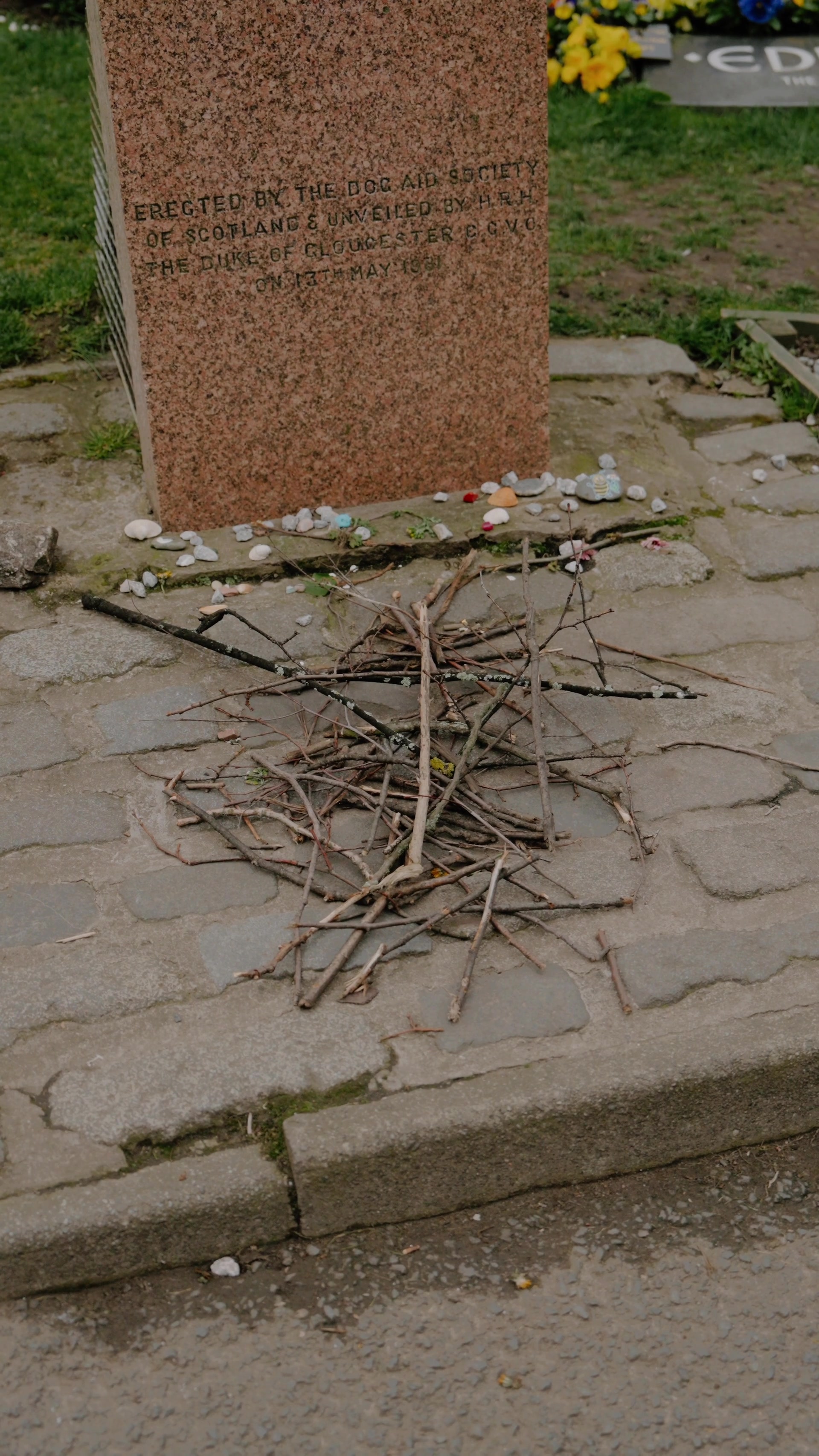 the base of Greyfriars Bobby's headstone with pebbles and sticks left as tributes