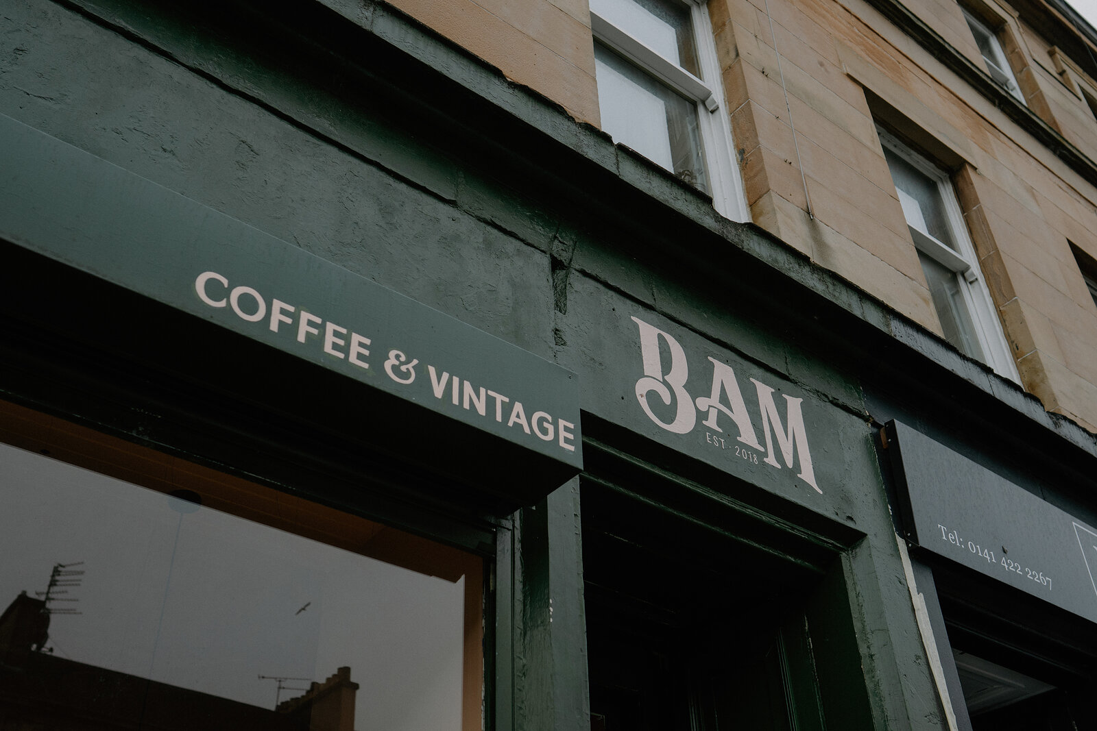 A dark green shopfront reads "Coffee and Vintage, BAM" in raised lettering above sash windows.