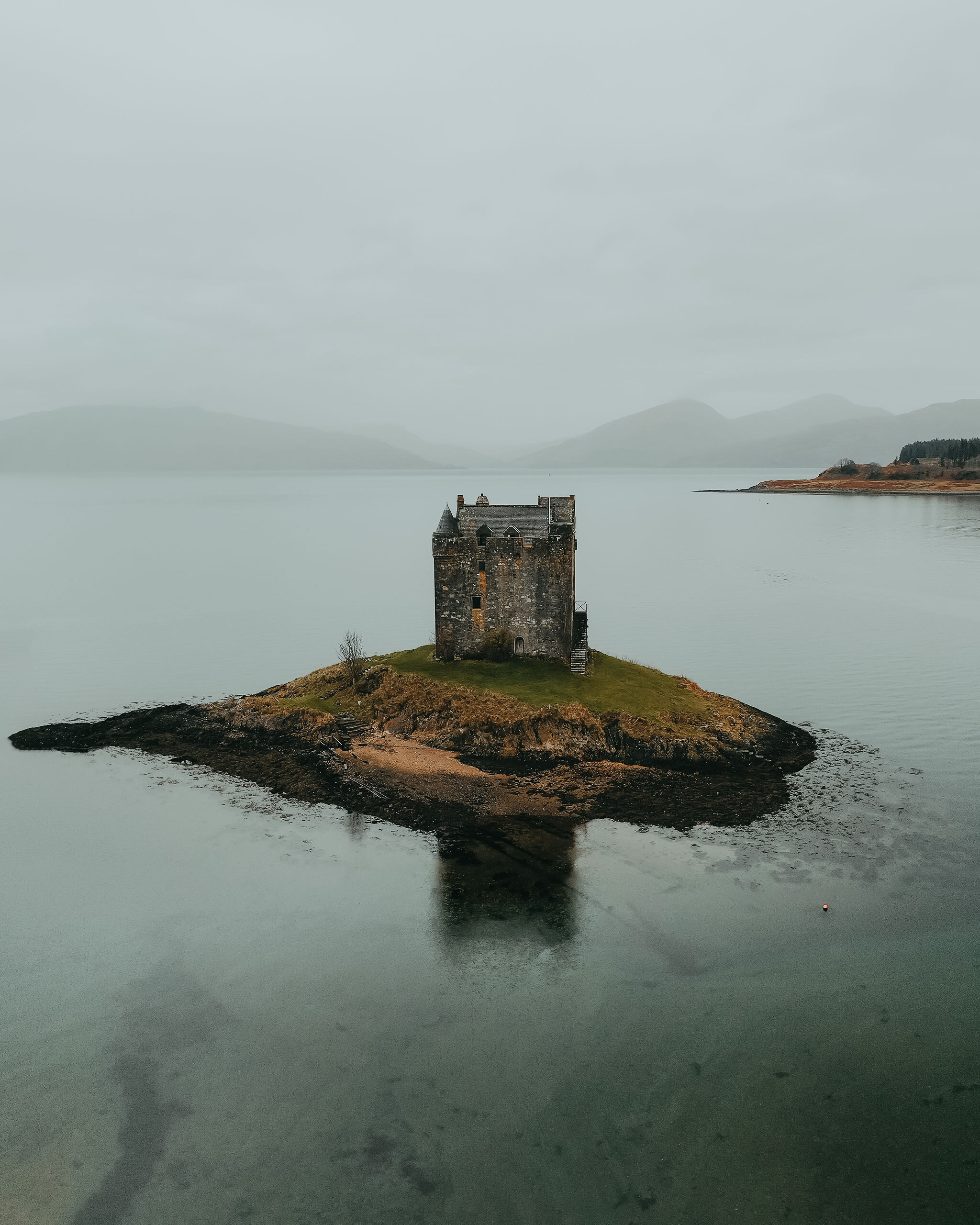 Castle Stalker on its tidal islet in Loch Laich, mirrored in still water under the mist.