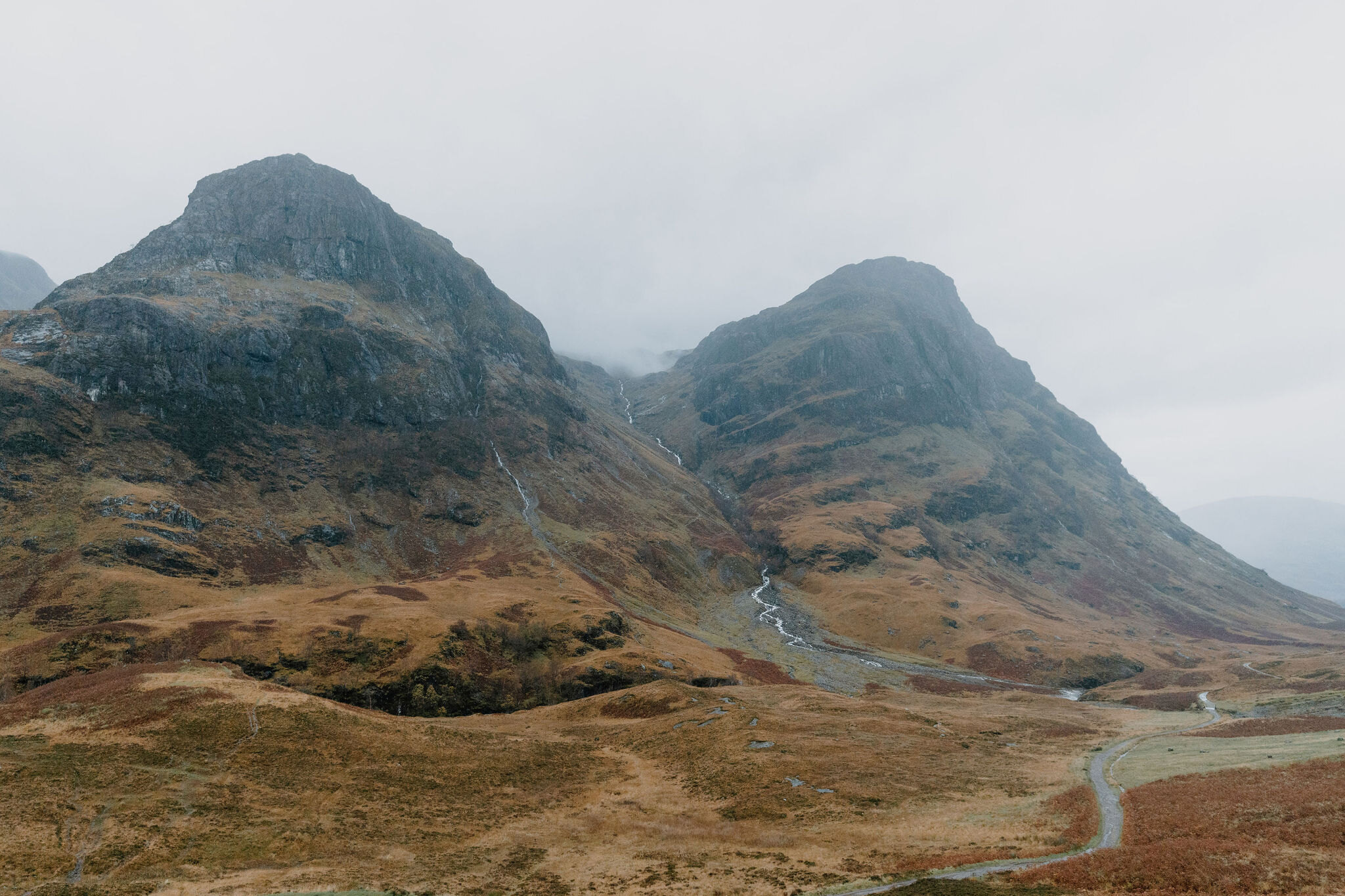 The Three Sisters over Glen Coe, the road winding through the heather below.