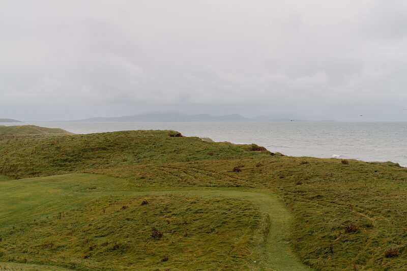 Dunes fall away toward the sea at Askernish, distant hills visible across the water.