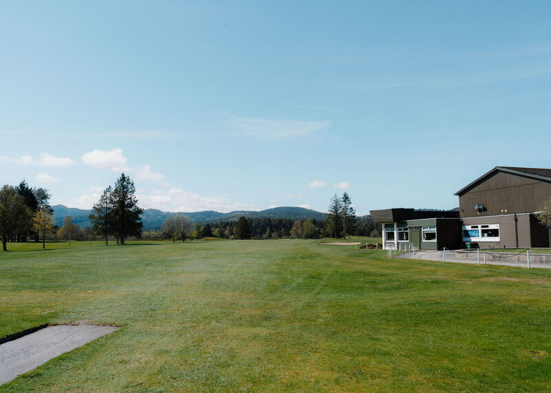 A fairway at Ballater Golf Club with the clubhouse on the right and hills beyond.