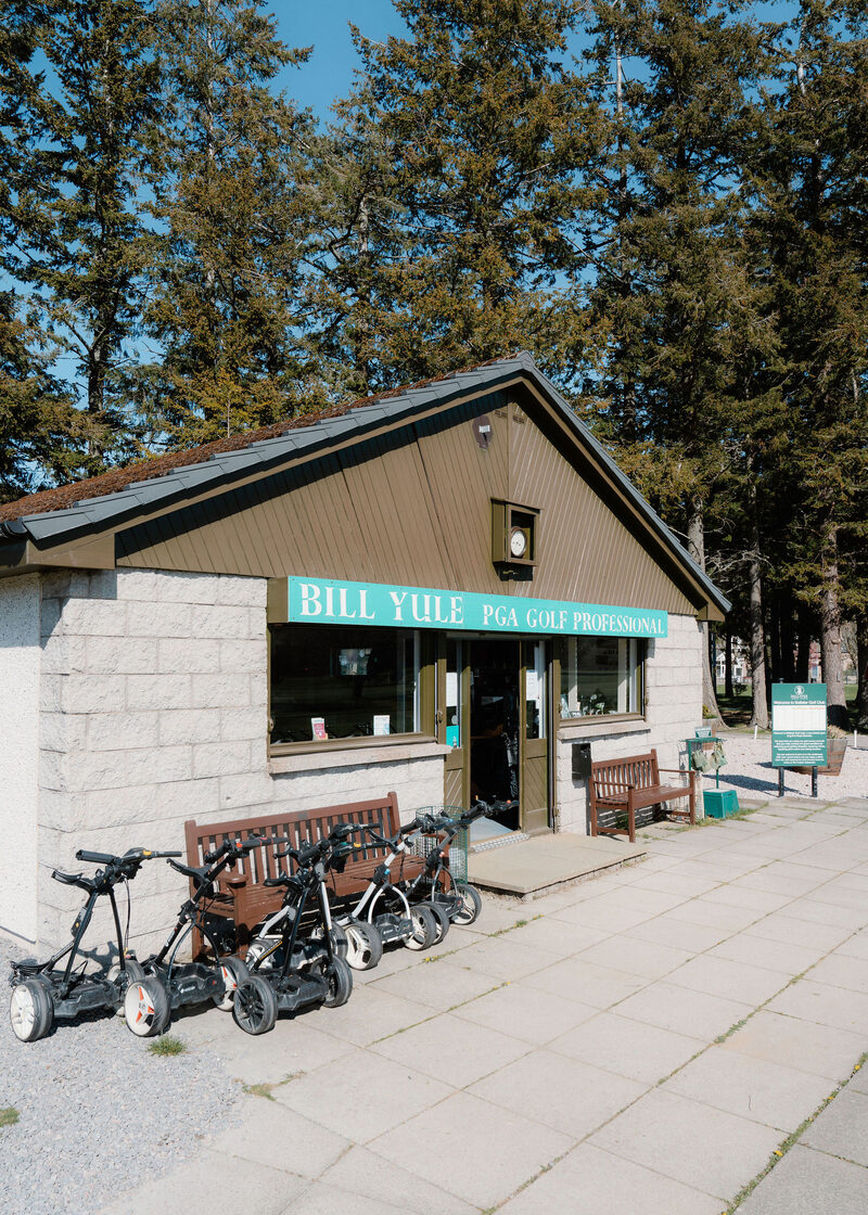 The professional’s shop at Ballater Golf Club, signed Bill Yule PGA Golf Professional, with trolleys and benches outside.