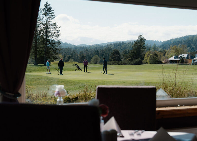Four golfers on a green, seen from the clubhouse restaurant window.