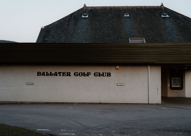 The clubhouse wall lettered Ballater Golf Club, by the car park at dusk.