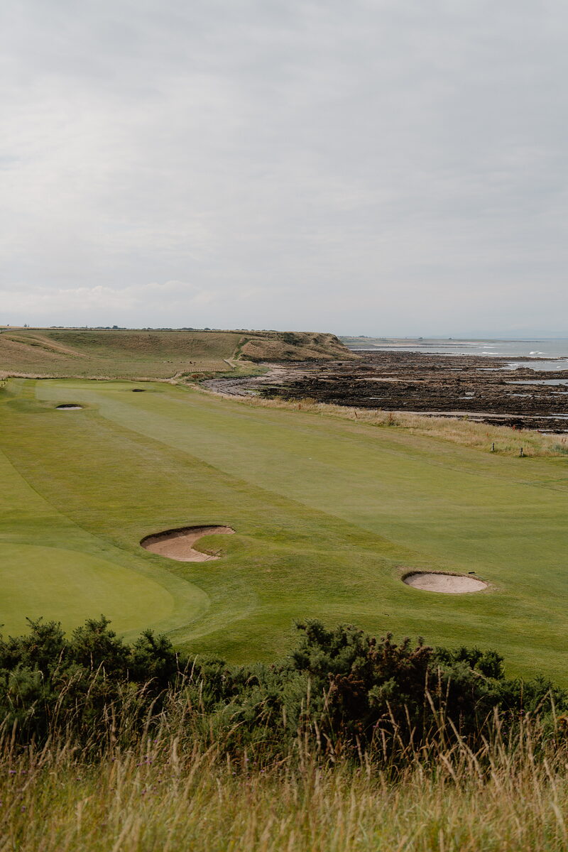 A fairway bordered by bunkers overlooking rocky coastline and the sea