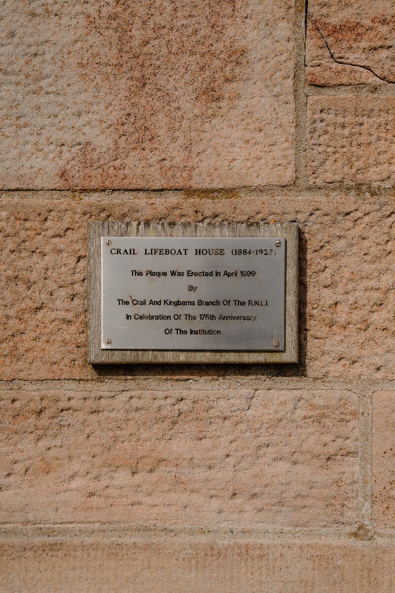 A plaque reading Crail Lifeboat House 1884-1925, mounted on a sandstone wall