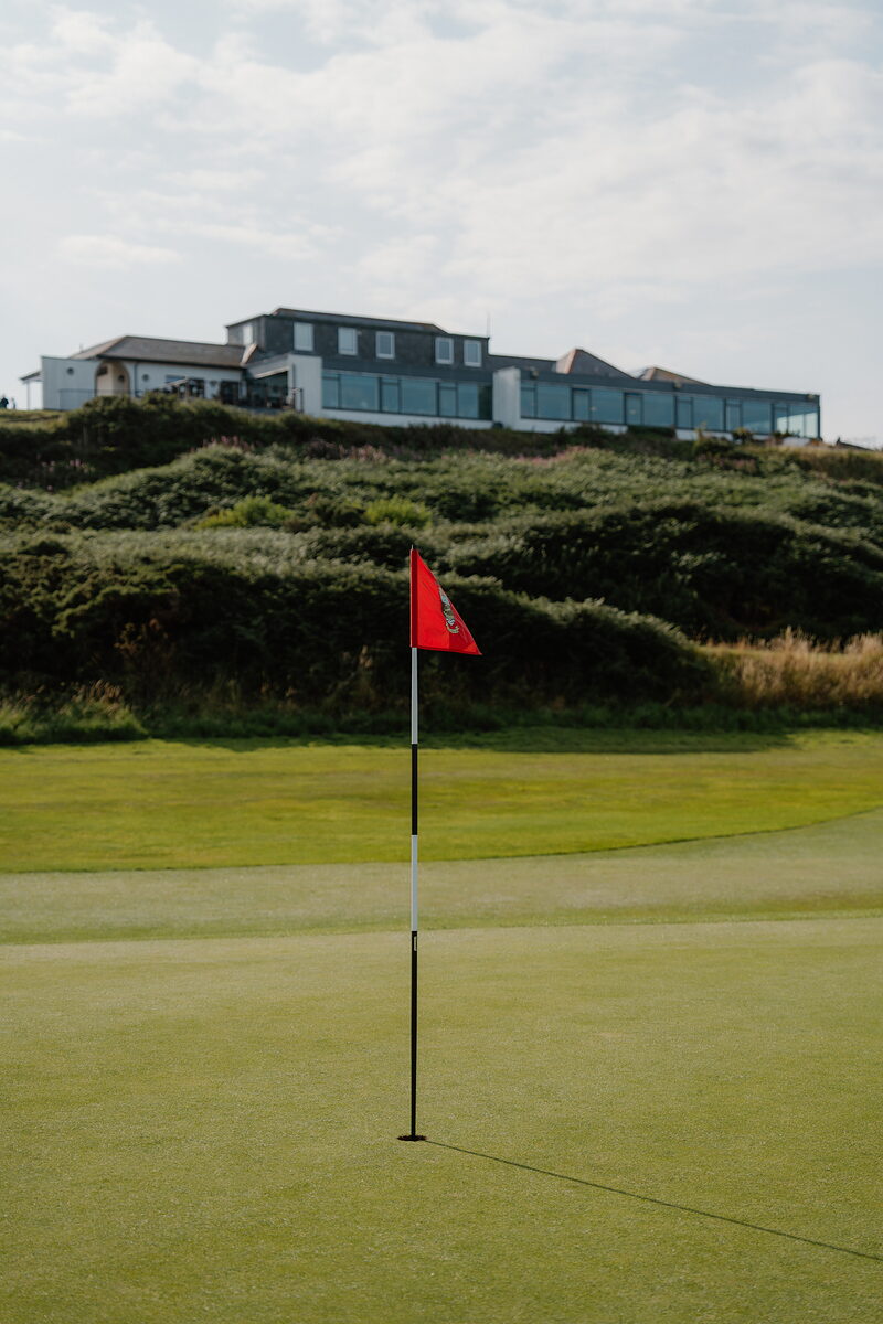 A red flag marking a green, a clubhouse perched on a rise above the dunes