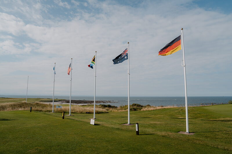 A row of national flags flying on a bank above the sea at Crail