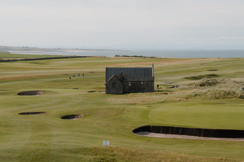 A stone shelter and bunkers on the fairway at Crail, with the coastline stretching into the distance.