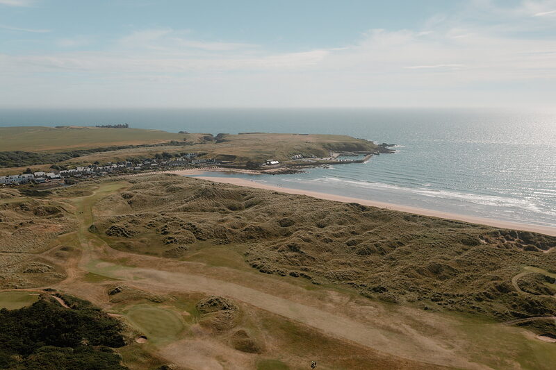 Rolling dune fairways stretching towards a sandy bay and village on a links course