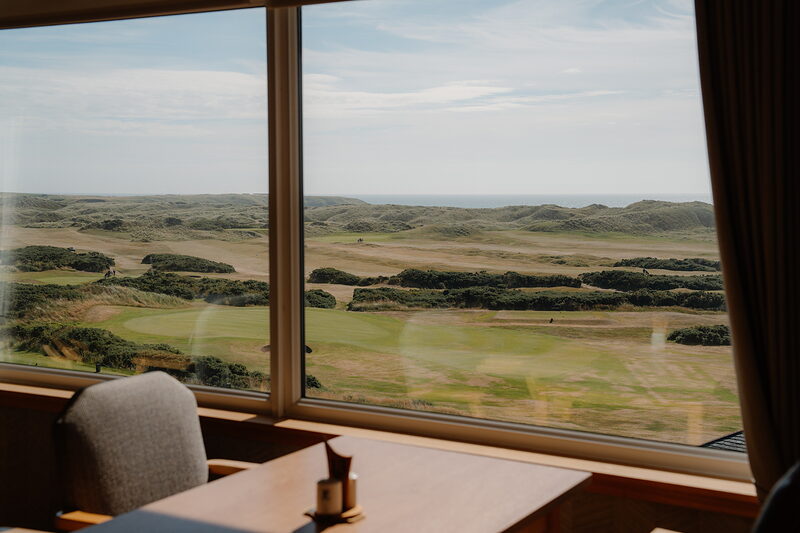 A dining room window framing dune fairways stretching towards the sea